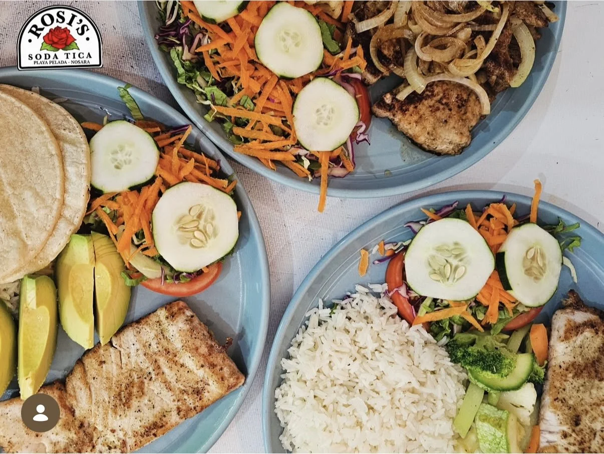 Three plates of grilled fish, rice, salad with cucumber and tomato, lemon wedges, and bread, with Rosy's Soda Tica logo in the top left corner.