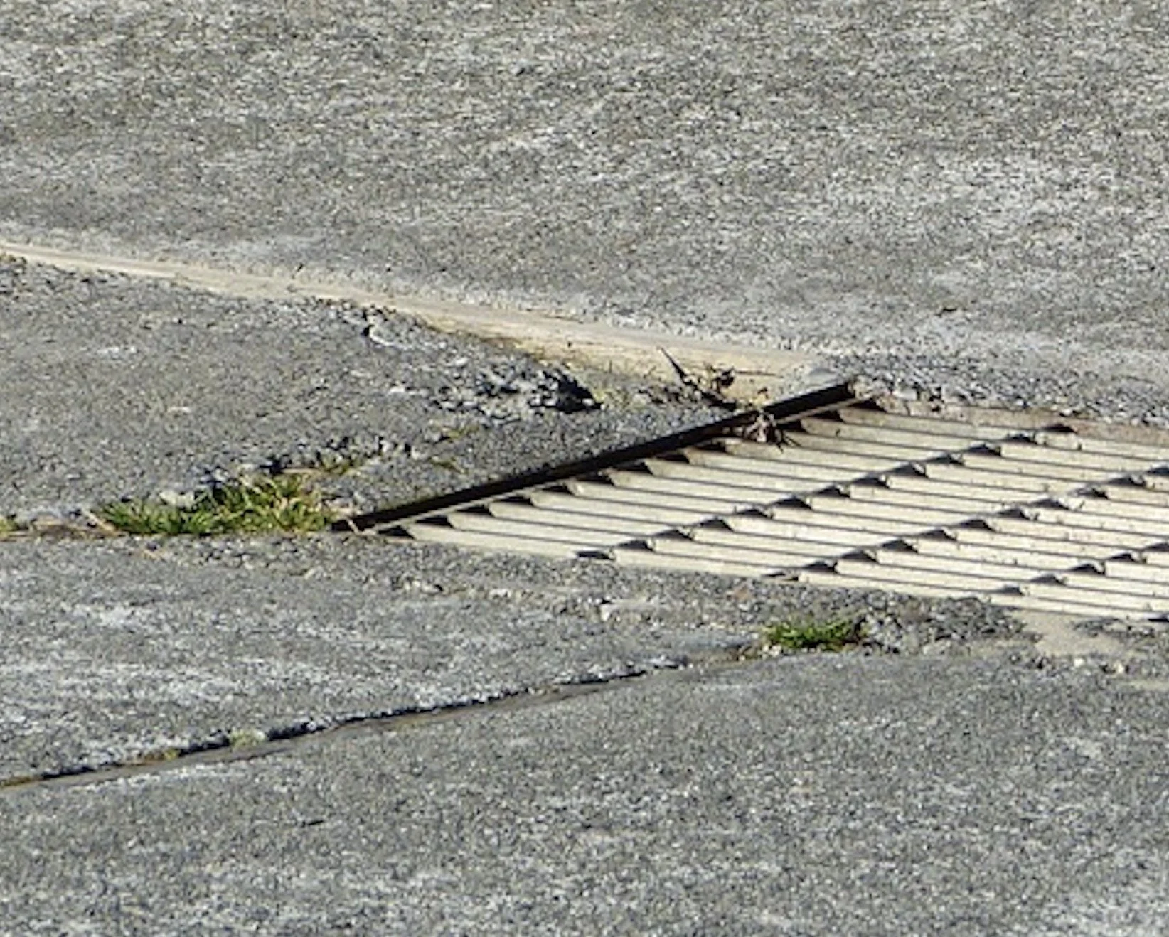 Cement surrounding the drain is deteriorated so bad that water runs under the driveway instead of into the drain.