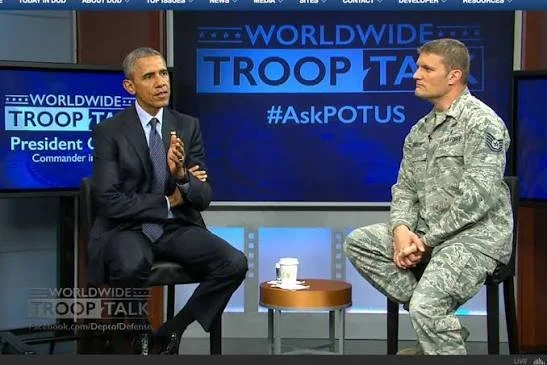 President Obama and a soldier in uniform in a televised interview setting, discussing troop talk.
