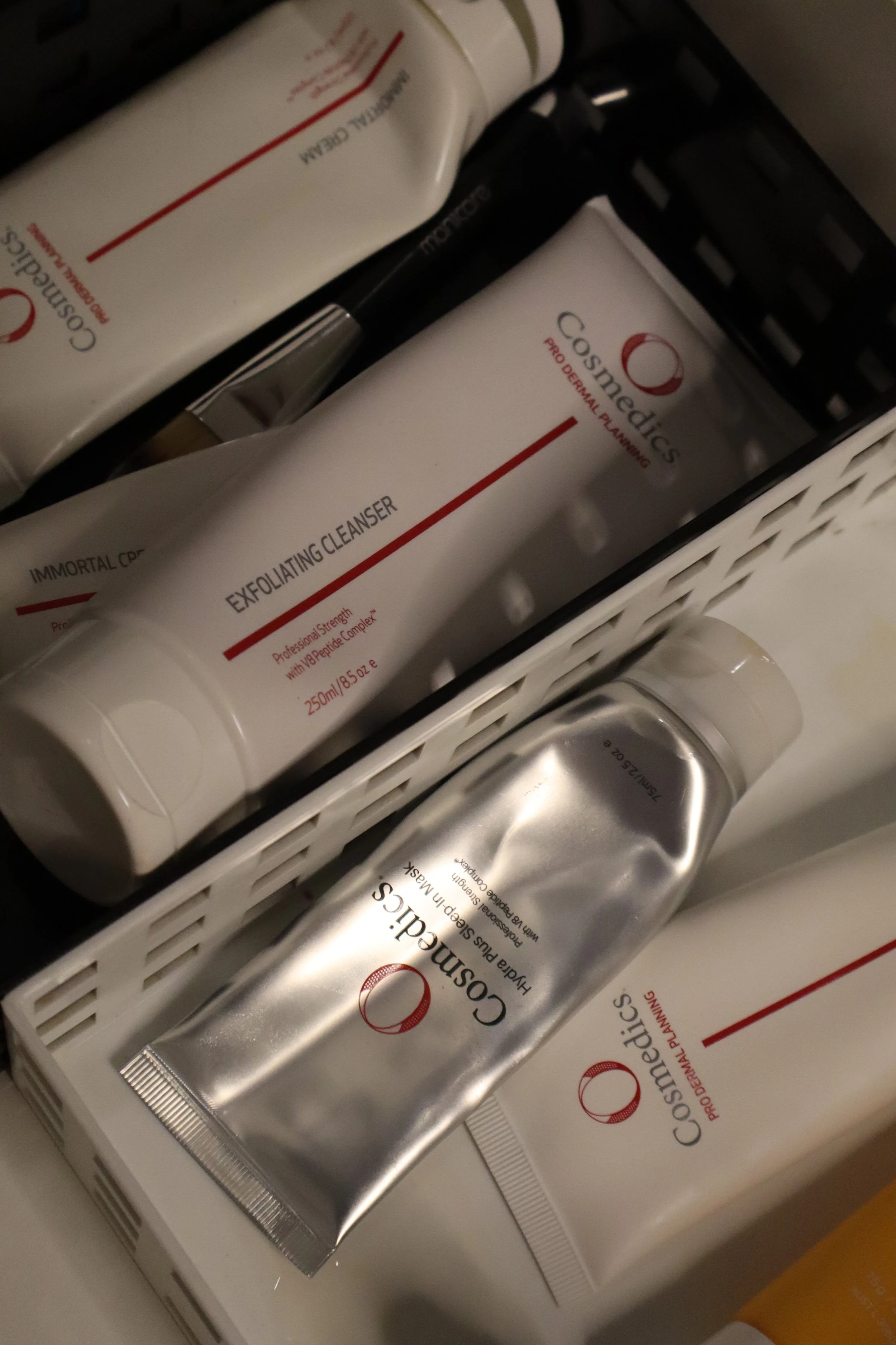 Collection of skincare products including exfoliating cleanser and hydrating mask from Cosmedics, in a white plastic basket.