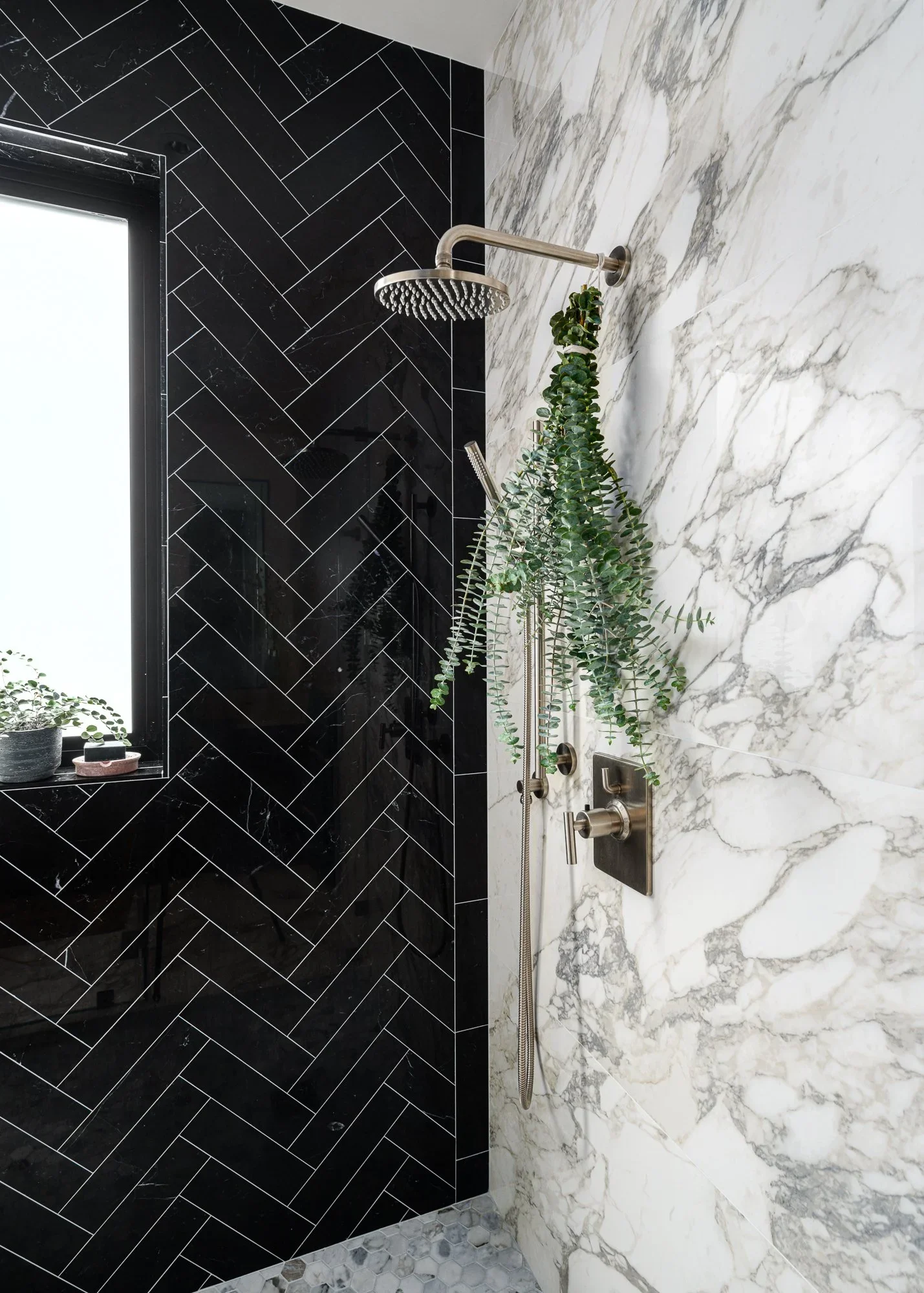 Primary shower with black herringbone tile accent wall, white Calacatta marble slab surround, brushed nickel rain showerhead, and hanging eucalyptus — Pacific Heights San Francisco by Mokume Design Studio