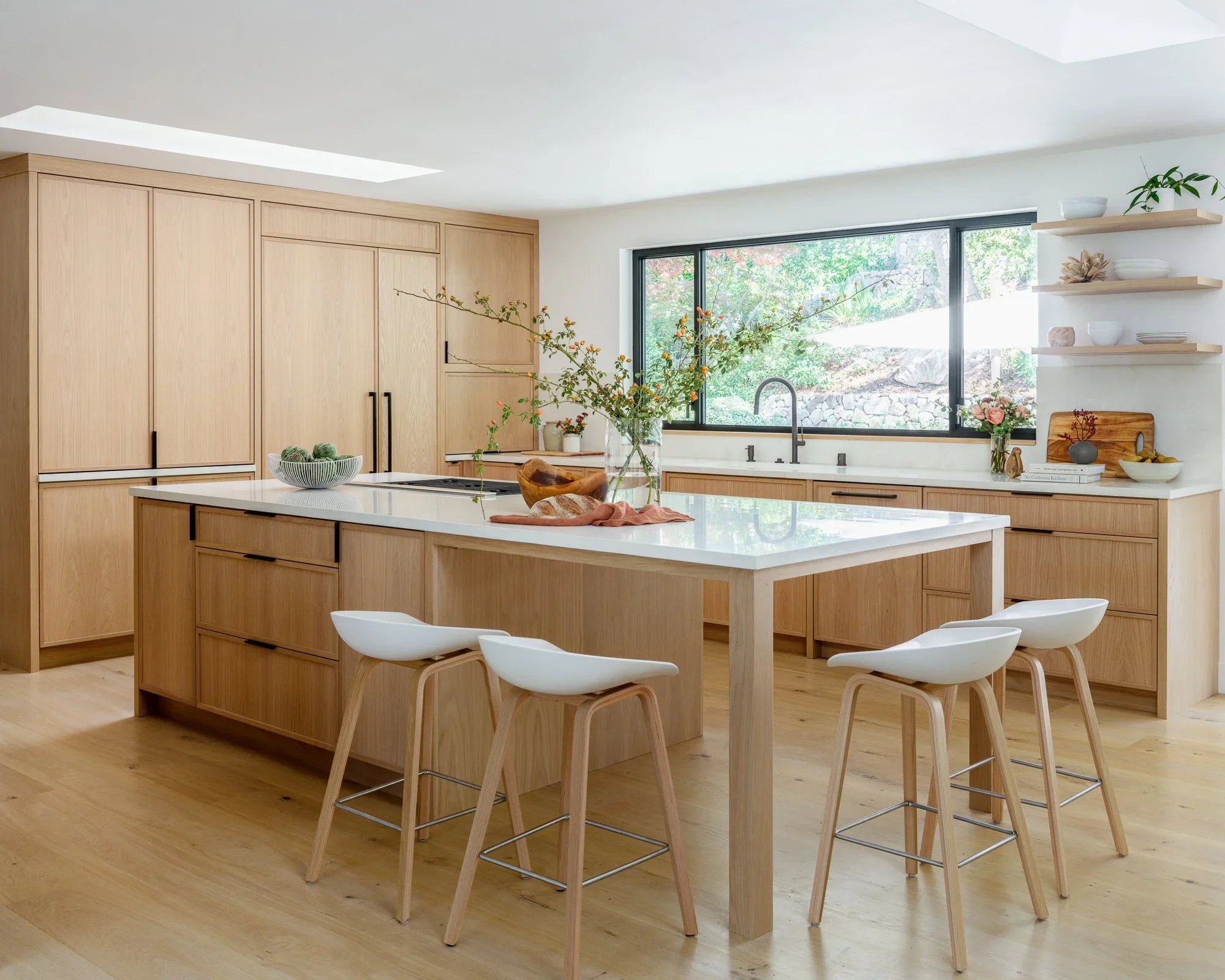 Custom natural oak kitchen cabinetry with built-in Wolf double wall oven, open shelving, and steel-framed glass door leading to entryway — Lafayette California home remodel by Mokume Design Studio