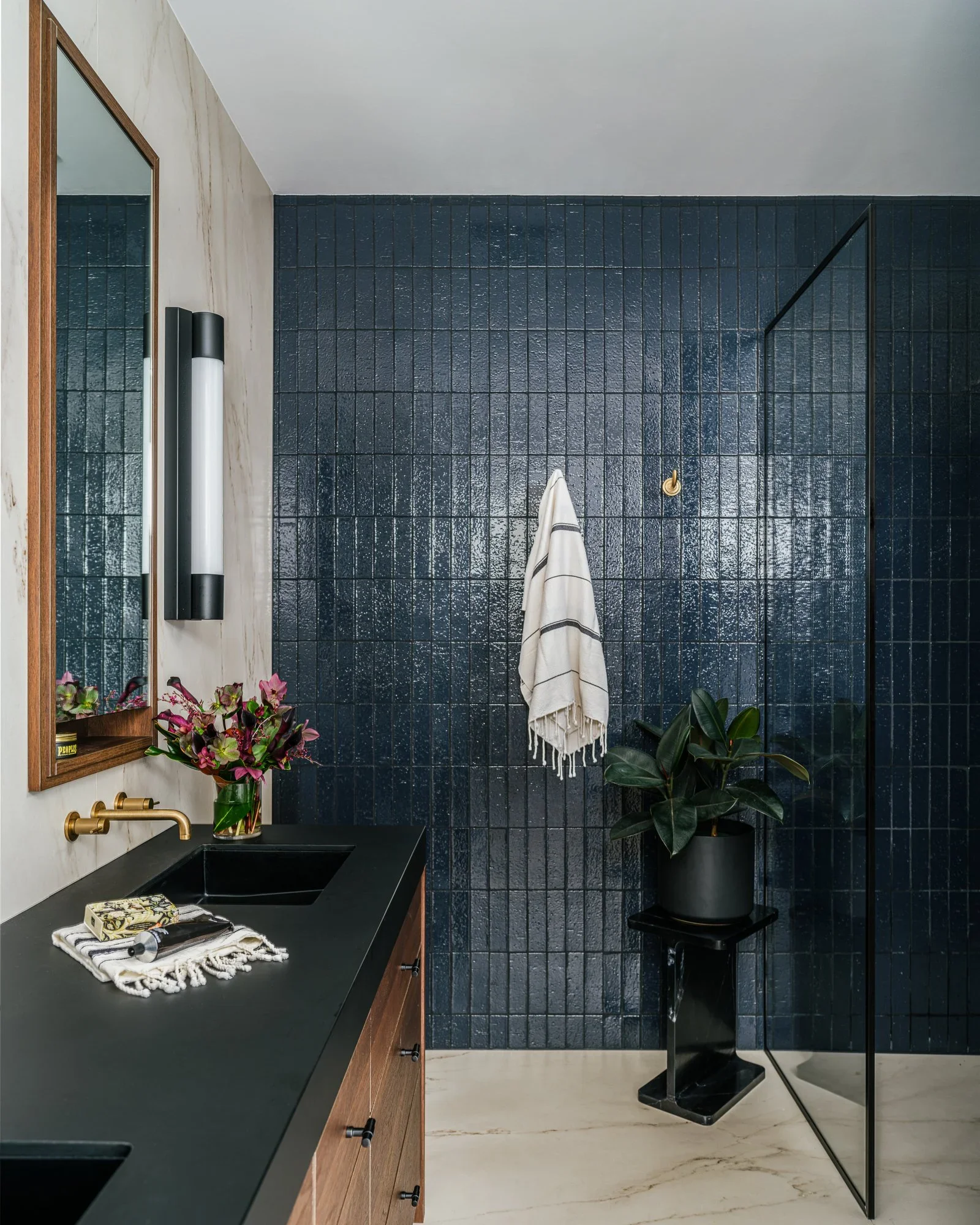 Bold navy glazed tile bathroom with black stone trough sink, walnut floating vanity, brass wall-mount faucet, and frameless glass shower enclosure — Hill Street Residence San Francisco by Mokume Design Studio