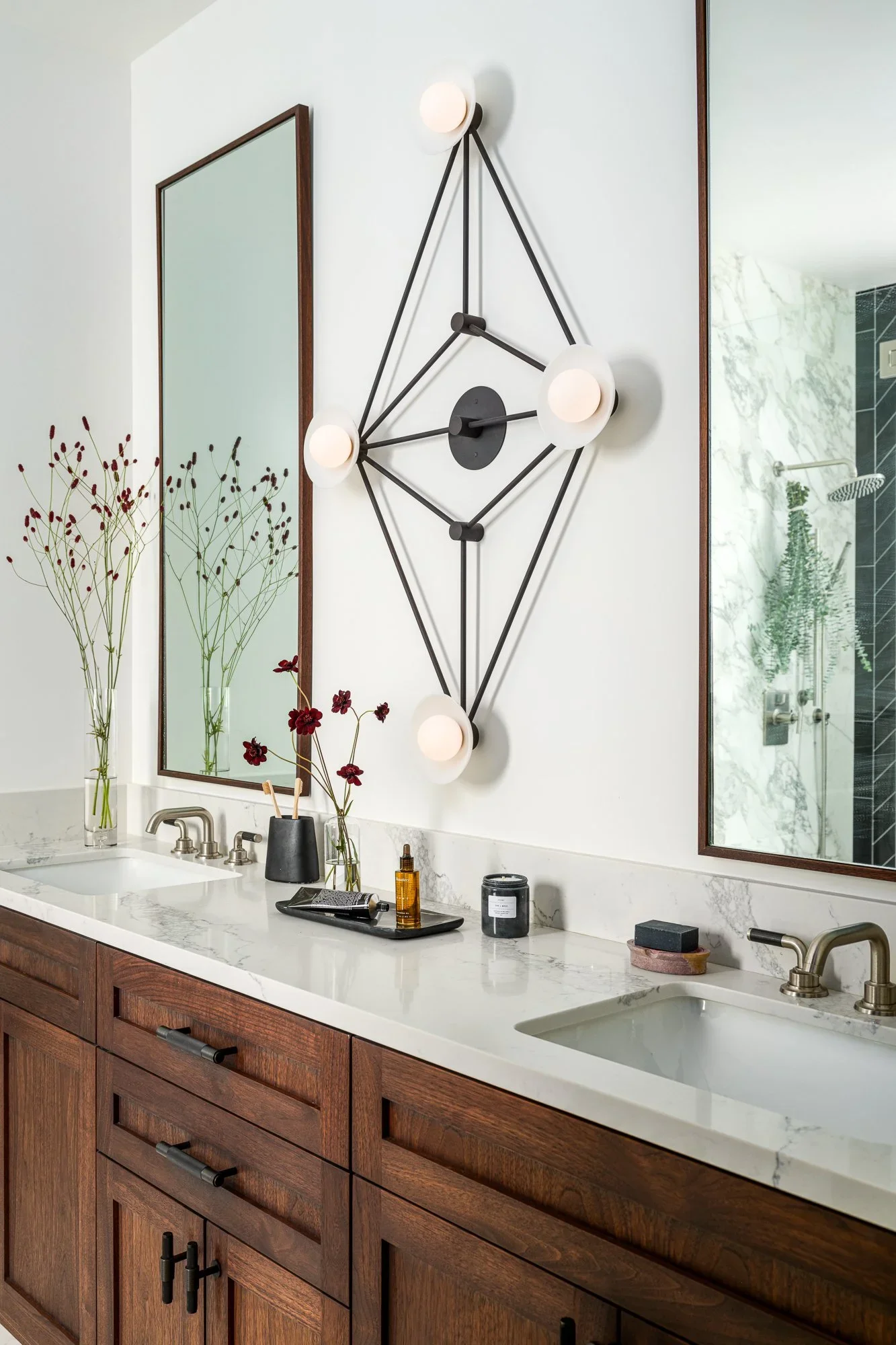 Primary bathroom double vanity with dark walnut cabinetry, white Calacatta marble countertop, walnut-framed mirrors, and sculptural black multi-arm globe sconce — Pacific Heights San Francisco by Mokume Design Studio