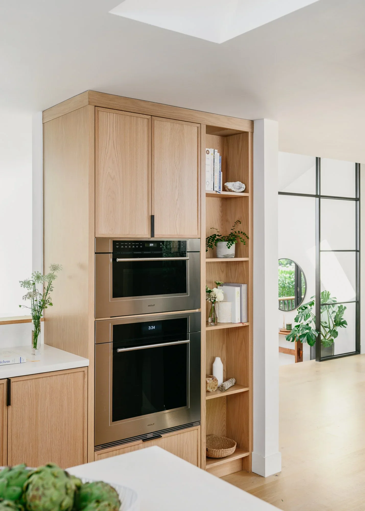 Natural oak kitchen with integrated coffee bar, panel-ready refrigerator, and black matte hardware on wide-plank hardwood floors — Lafayette California home remodel by Mokume Design Studio