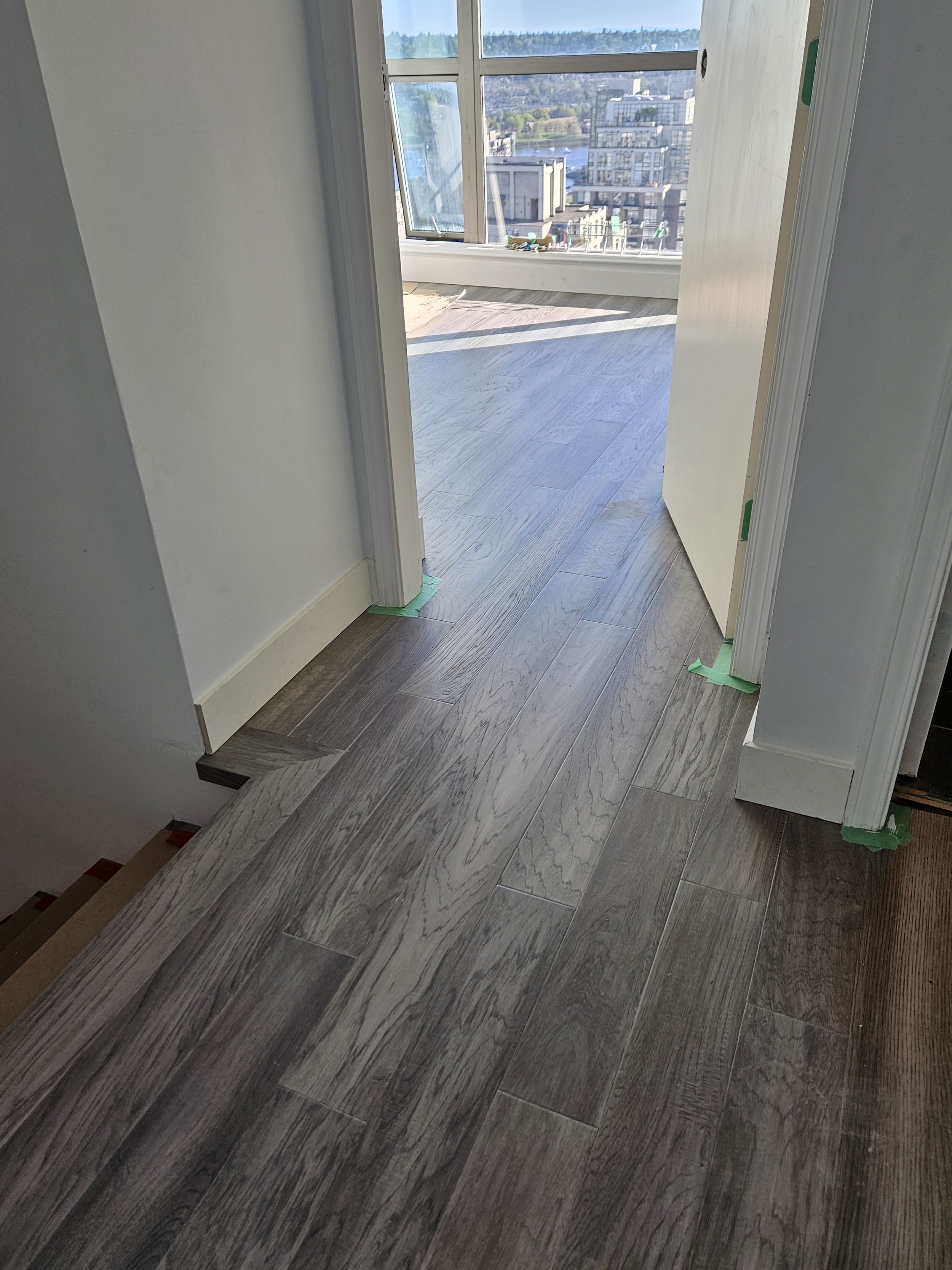 Room with newly installed dark wood flooring, an open door, and a balcony with city and river view.