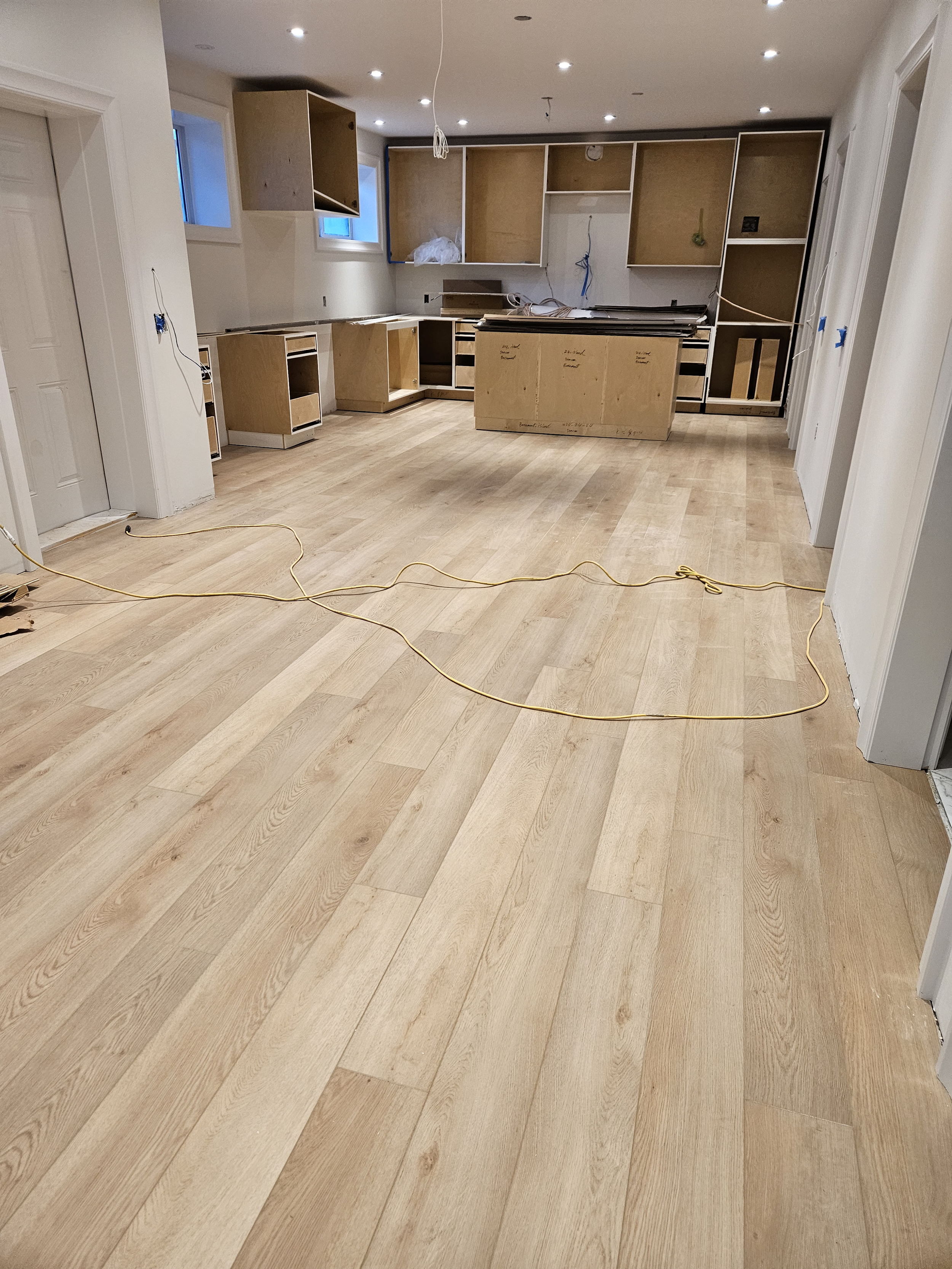 Under construction kitchen with unfinished cabinets and hardwood flooring.
