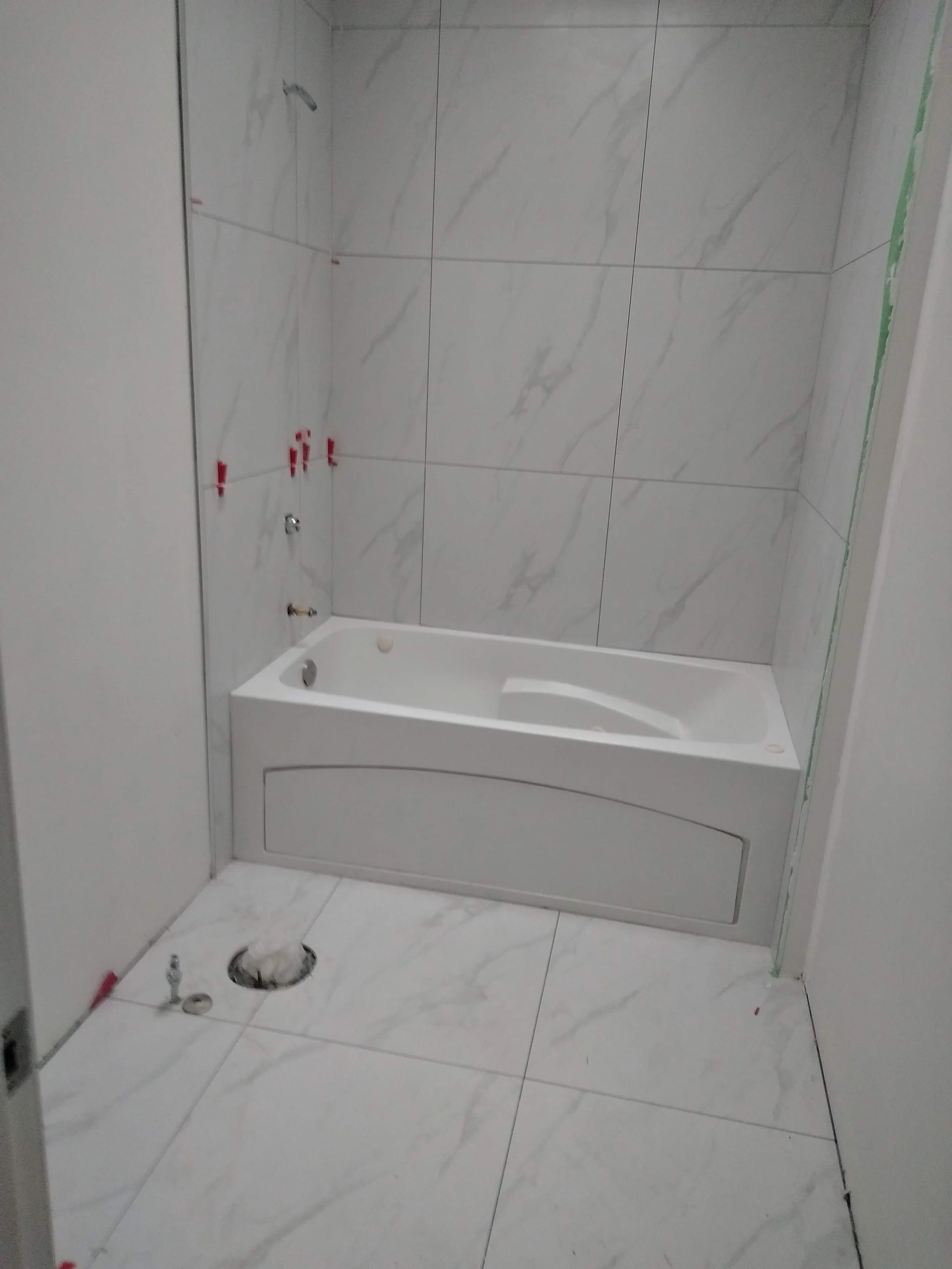 Bathroom under construction with a bathtub, tiled walls, and plumbing fixtures.