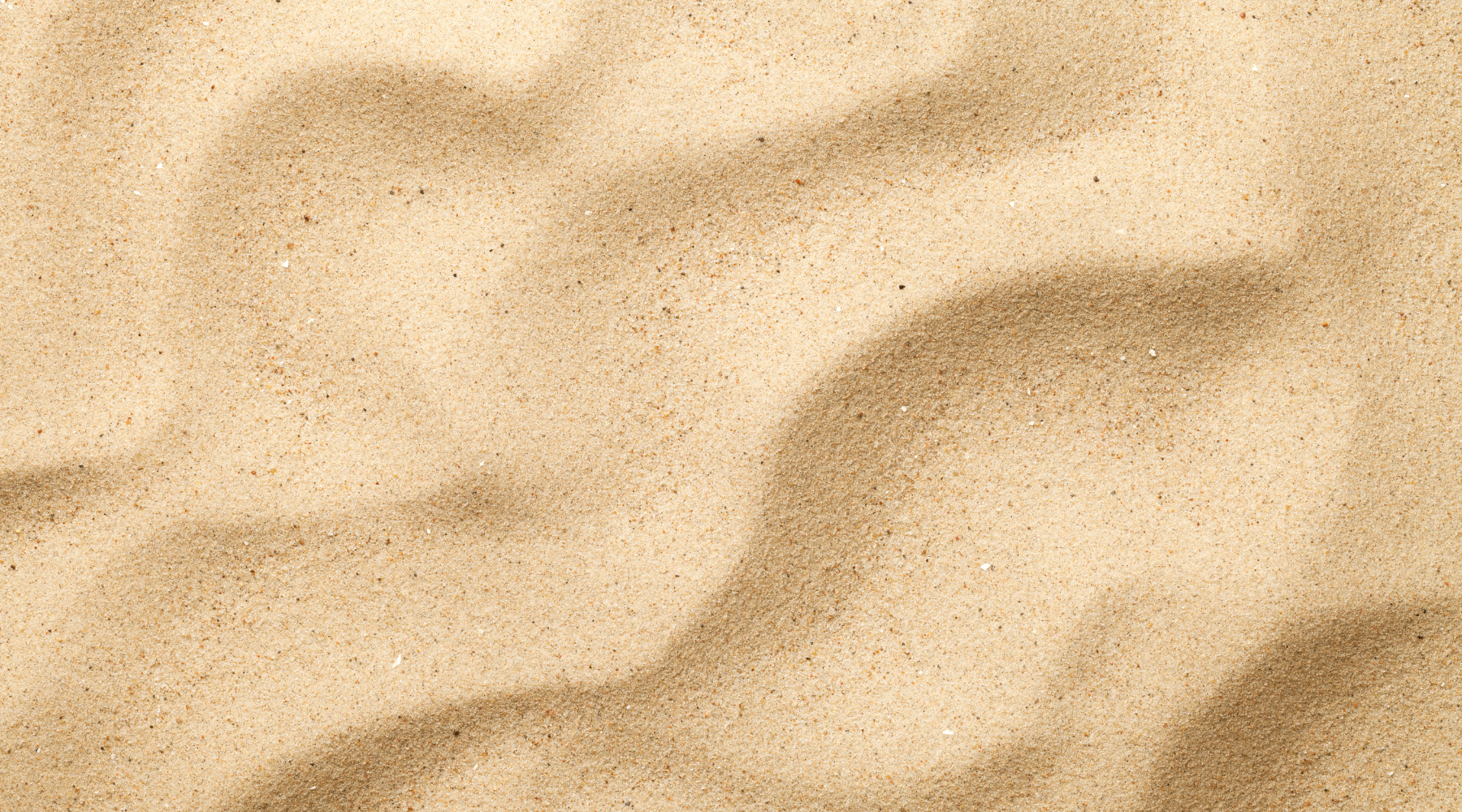 Close-up of soft sand with natural wavy ripples.
