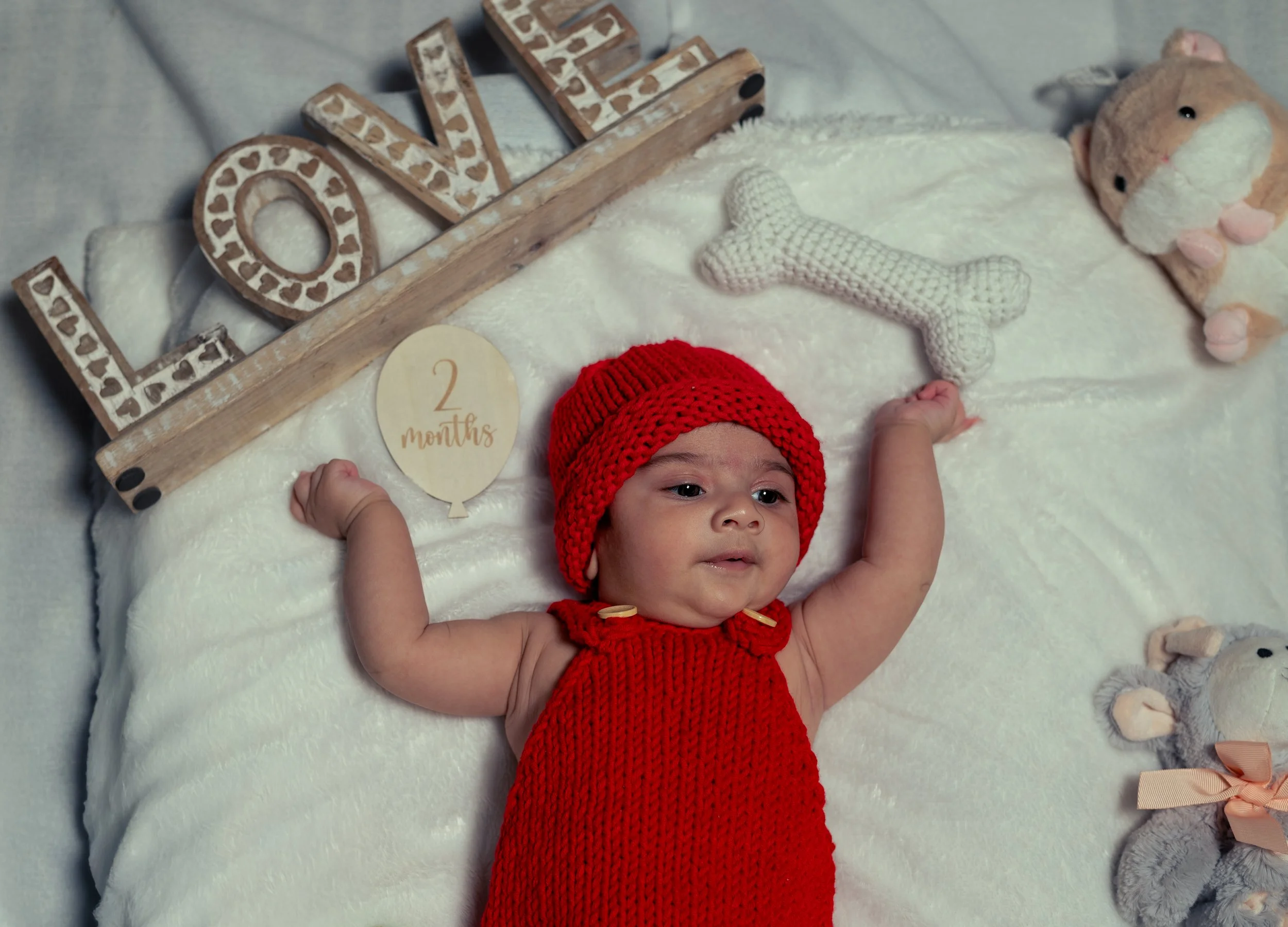 Baby girl in red dress with LOVE sign at 2 months milestone | Newborn Photography Kitchener Ontario by Abhijeet Bhullar