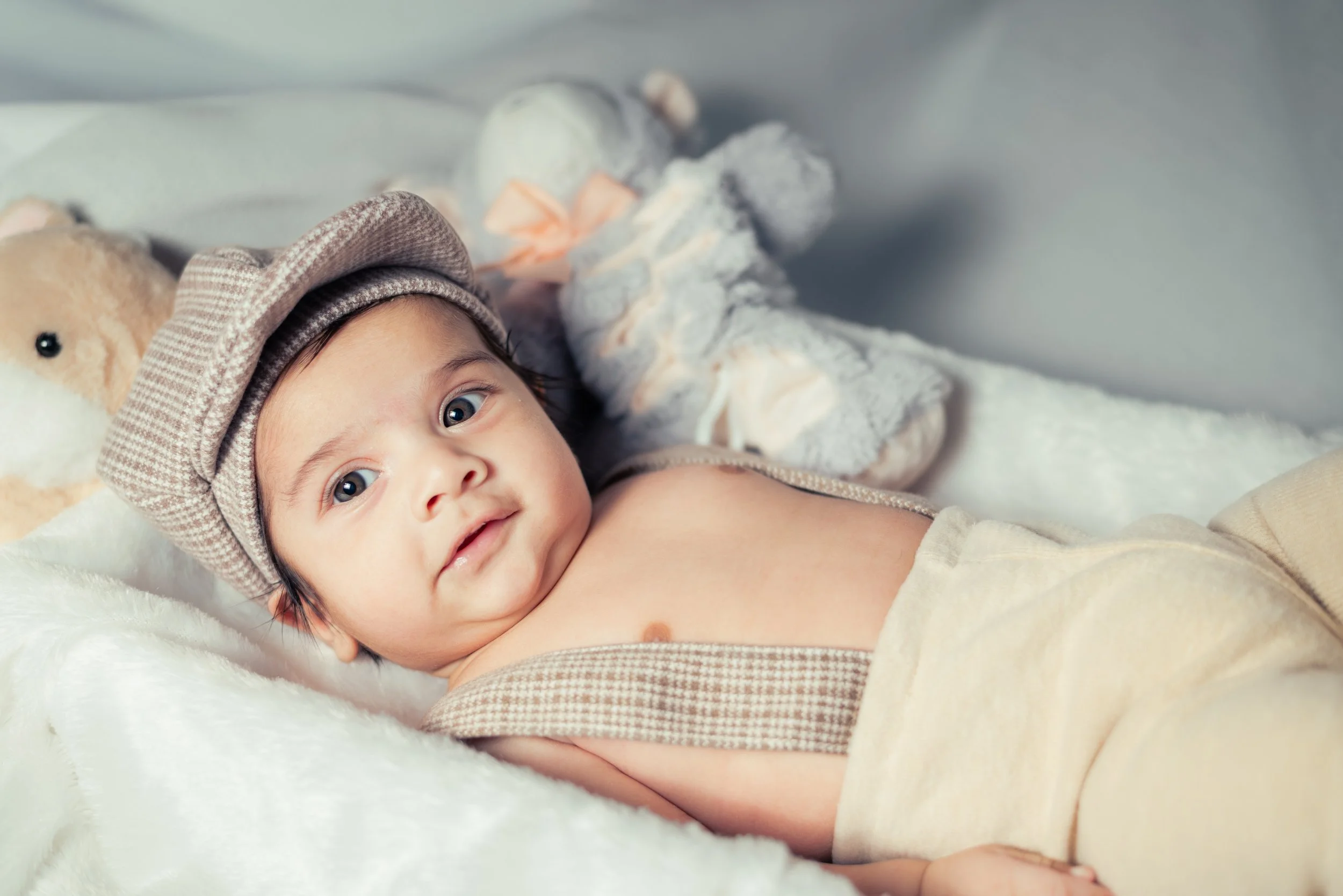 Newborn baby boy in flat cap with stuffed animals | Family & Newborn Photography Kitchener Ontario by Abhijeet Bhullar
