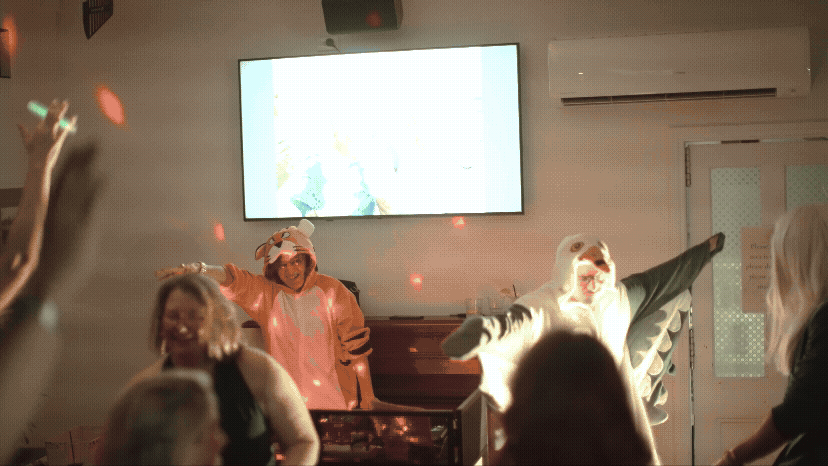A couple in animal onsies DJing at their own wedding