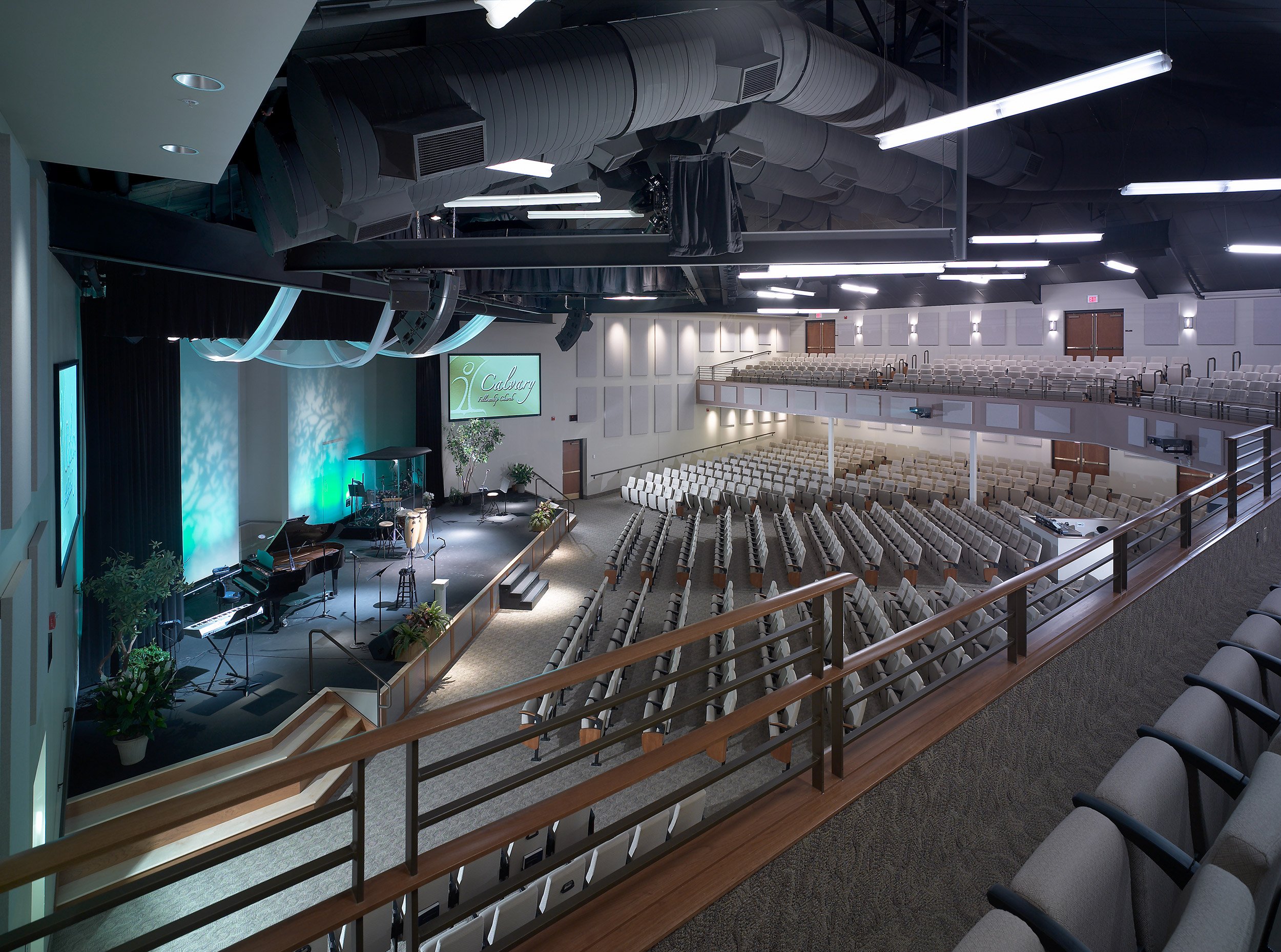 Empty church auditorium with a stage prepared for worship, featuring musical instruments and a large screen displaying 'Calvary'.