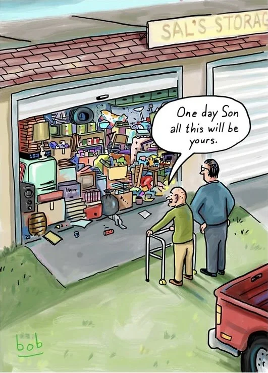 An elderly man using a walker and a middle-aged man standing next to him look into a cluttered storage unit filled with various items. The middle-aged man says, 'One day son, all this will be yours.'