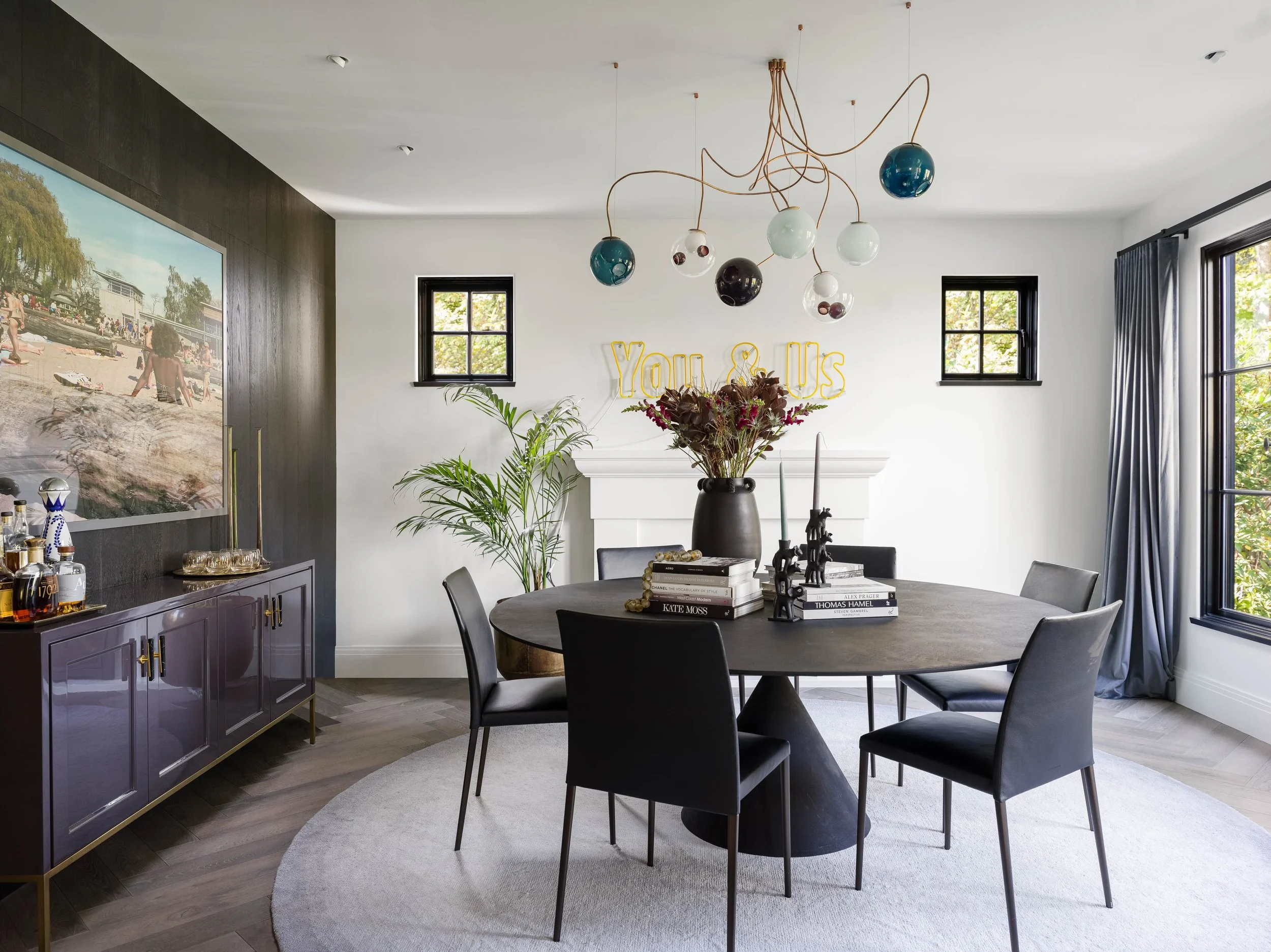 A dining room made for long dinners, second pours, and the kind of conversation that runs well past dessert. 

We let the room&rsquo;s quiet, moody palette do the heavy lifting. A black wood wall, a custom plum lacquered sideboard with elegant brass 