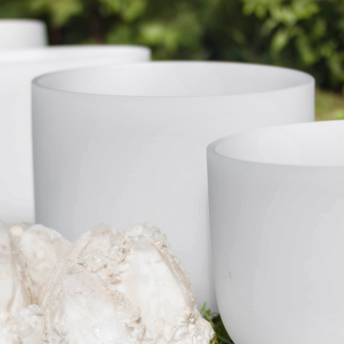 Close-up of large white cylindrical indoor or outdoor planters with a blurred green background.
