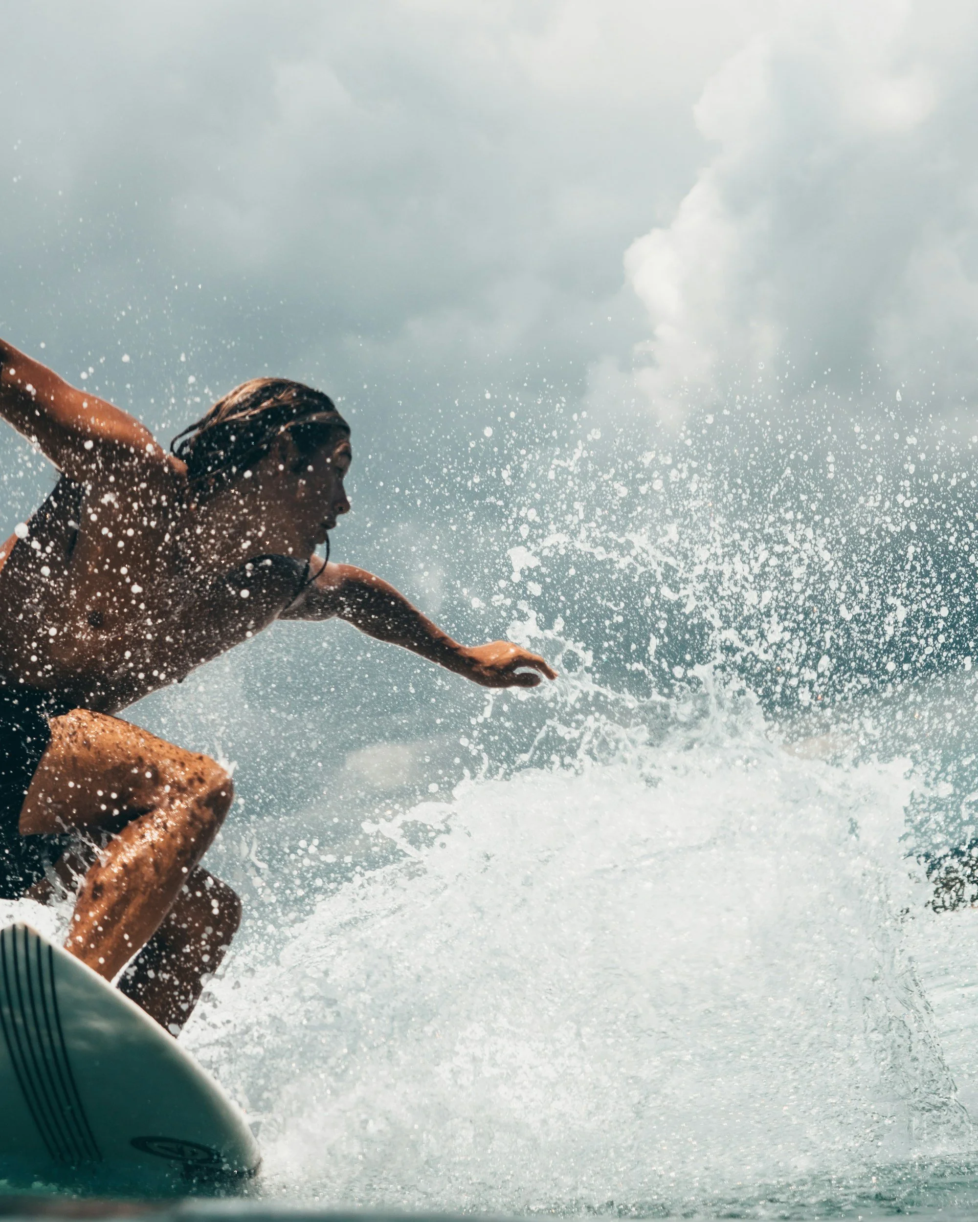 Person swimming in a pool, splashing water, with cloudy sky in the background.