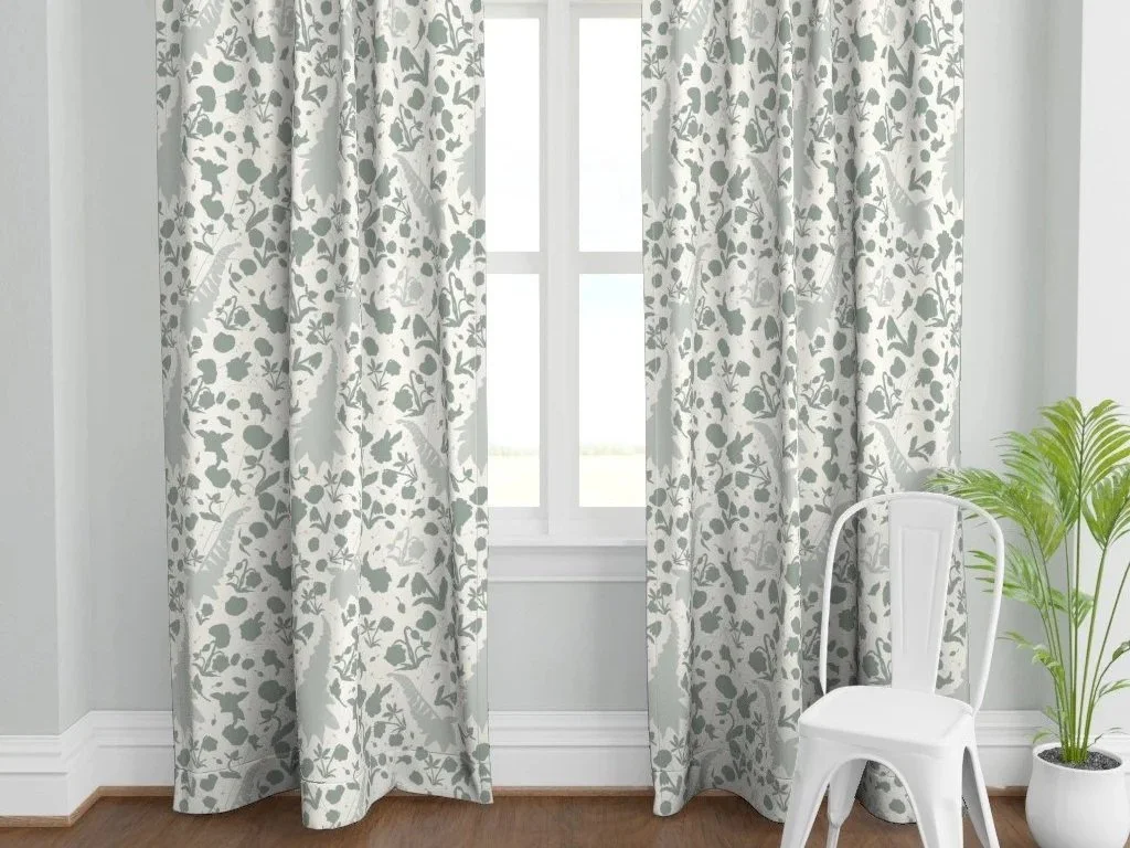 A window with light-colored floral curtains, a white chair, and a potted plant in a corner.