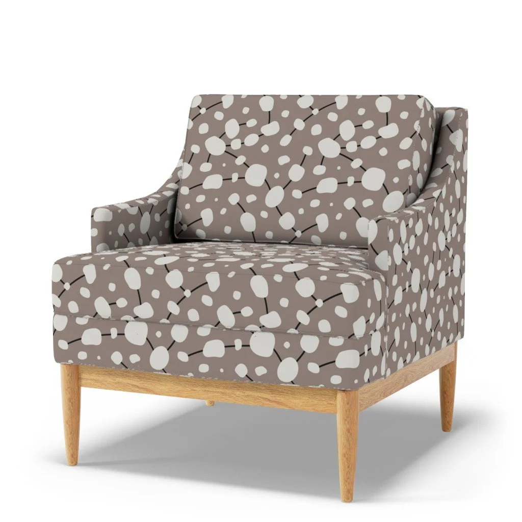 A modern armchair with a patterned fabric featuring white abstract dots connected by black lines, and a wooden base with tapered legs.