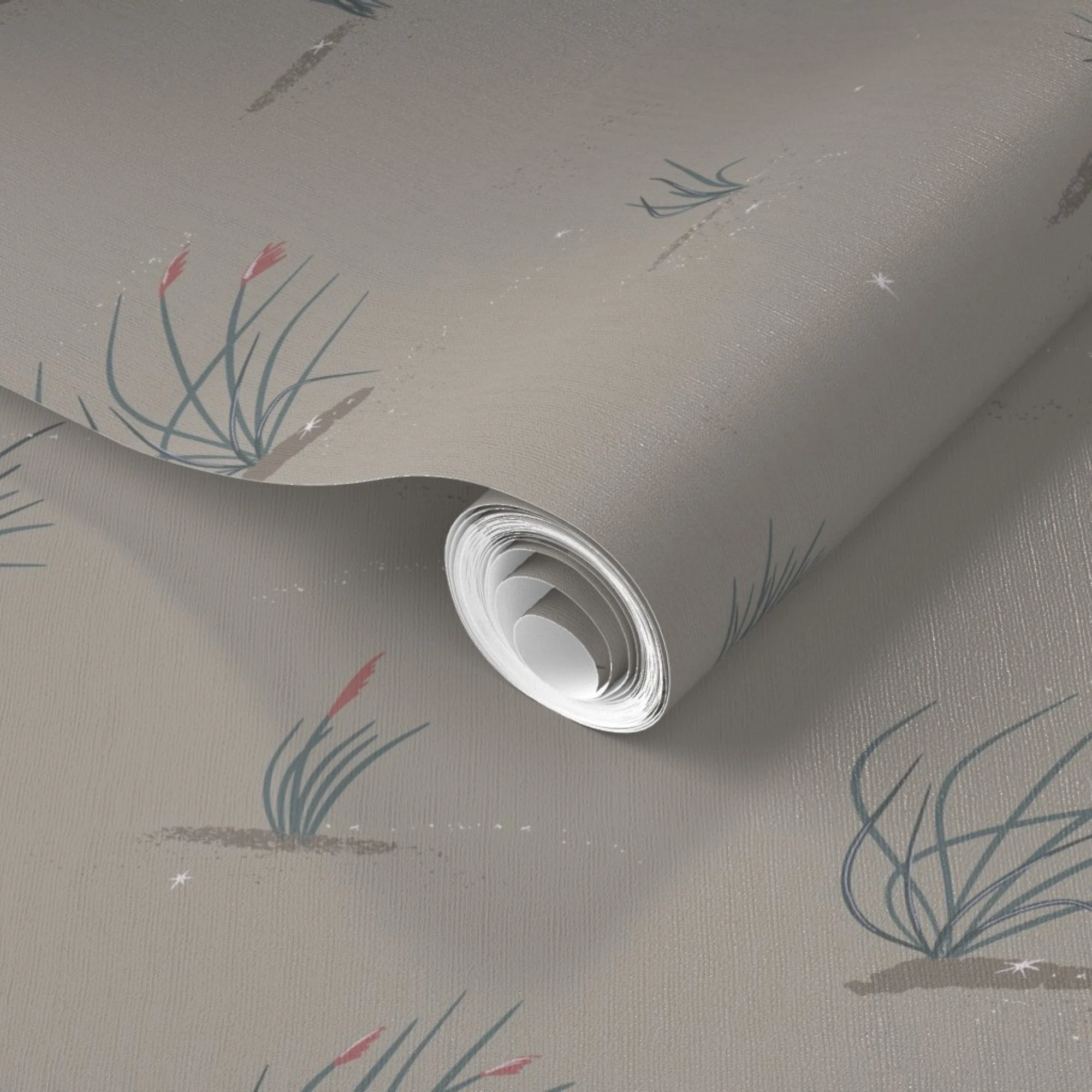 Close-up of a rolled-up piece of printed wallpaper with botanical dune grass illustrations, on a moody dark taupe surface with scattered star-like sparkles.