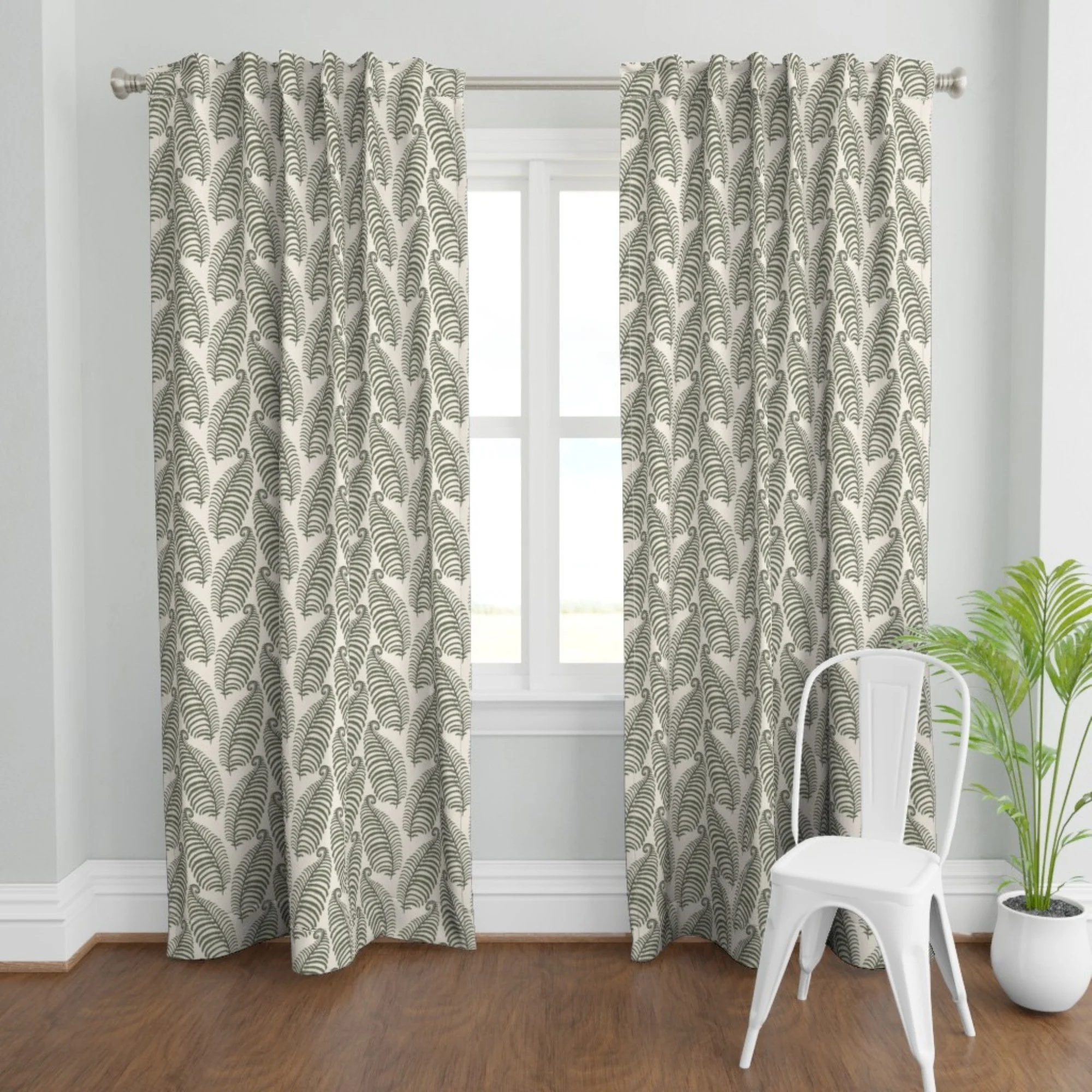 Patterned curtains with a fern leaf design hanging in front of a window, with a white chair and a potted plant nearby in a bright room.
