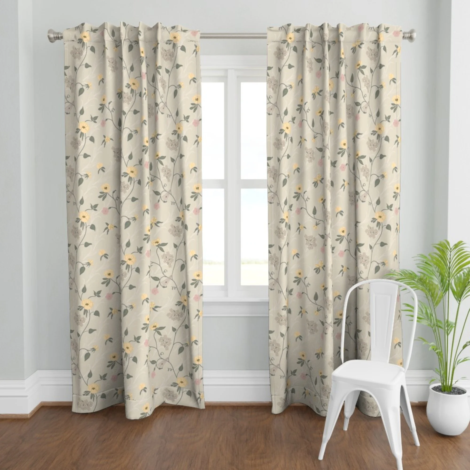 Cream-colored floral curtains hanging in front of a window in a room with hardwood floors, with a white chair and green potted plant nearby.