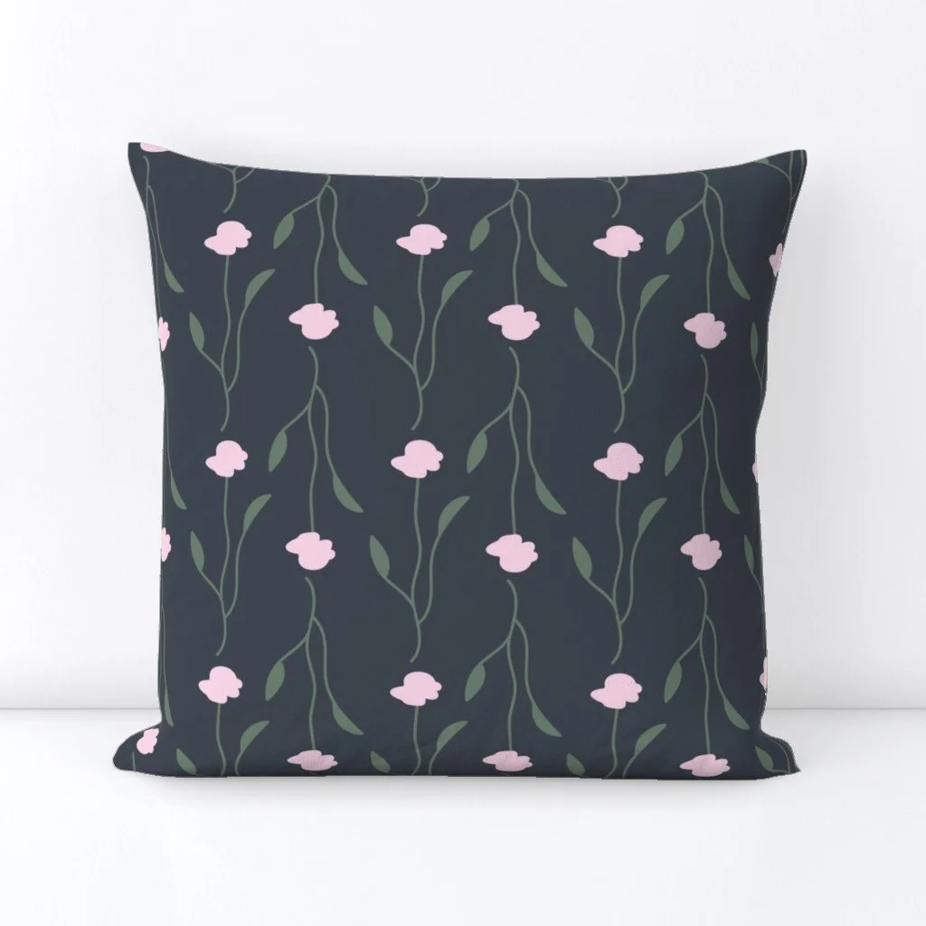 Square decorative pillow with a dark gray background and a pattern of pink flowers and green leaves.