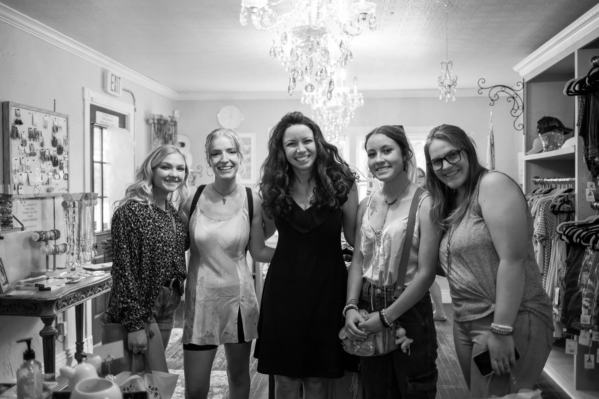 Group of five smiling women—including L.M. Thomas, the author, mentor and speaker—standing inside a store with a pretty chandelier, posing for a photo.