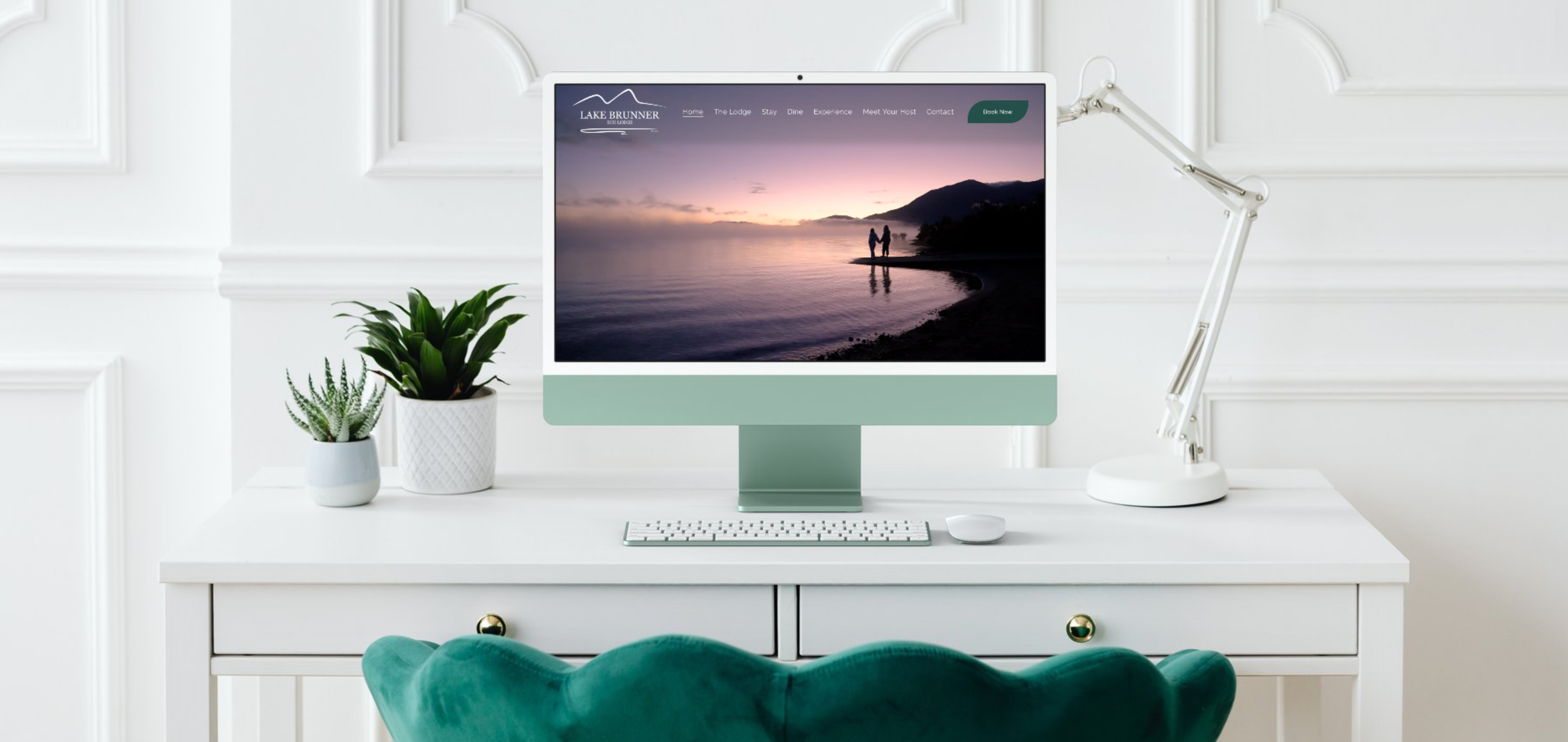 A modern white desk with a computer, showing a beautifully designed website on the screen.