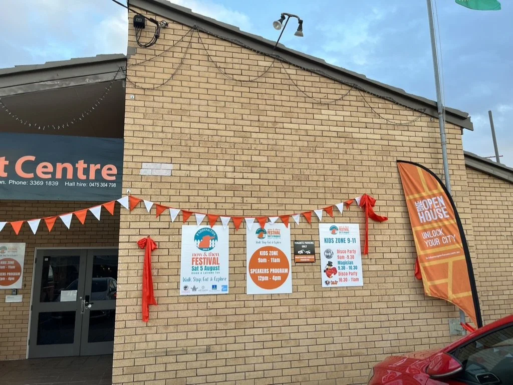 Brick building with promotional banners and signs for a festival called 'Boys & Then Festival' scheduled for Saturday, August 5th, featuring activities like a walk, stop, and explore. The signs also mention kids' zones, a speaker program from 12 pm t