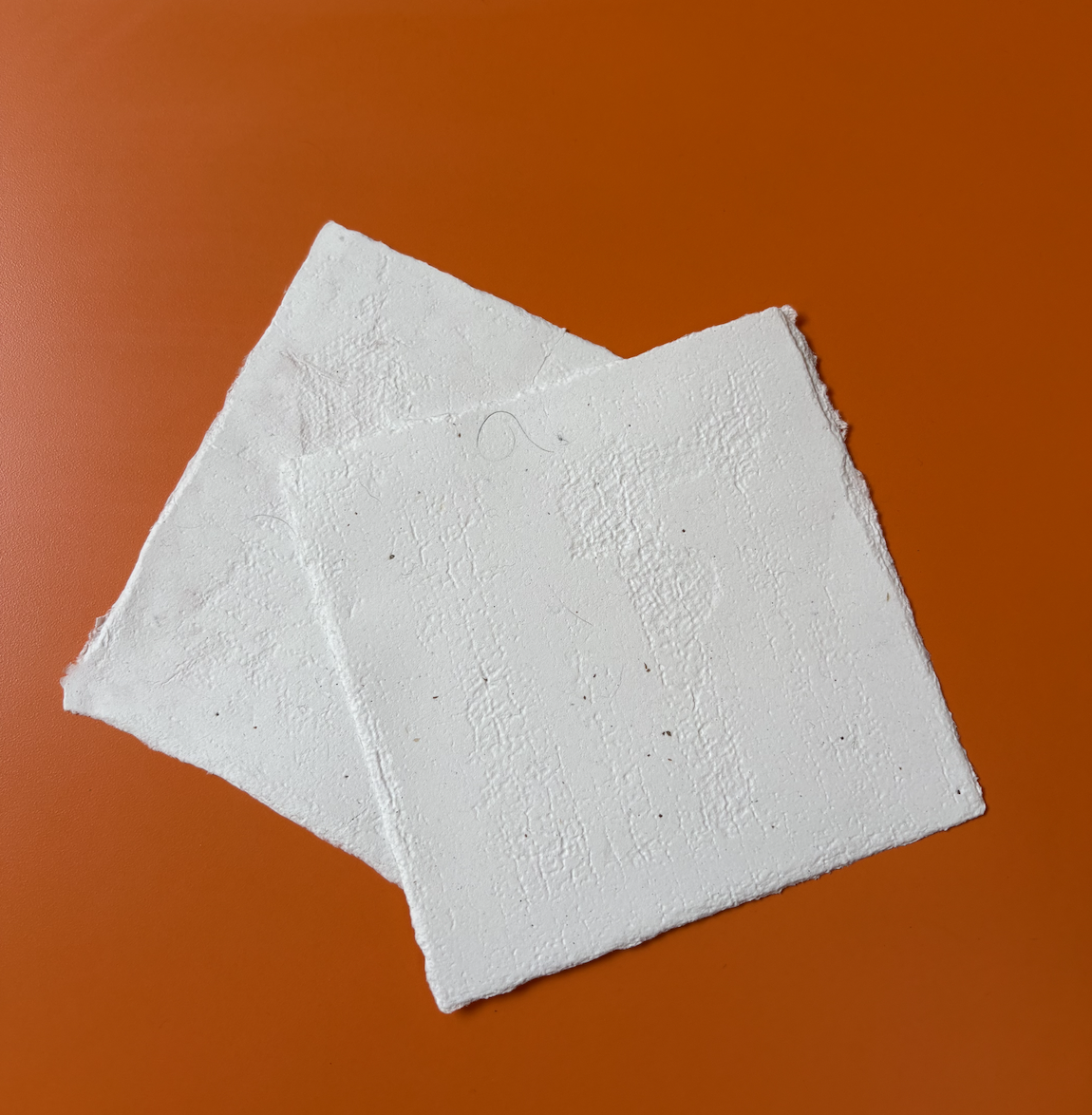 Two white foam boards stacked on an orange surface.