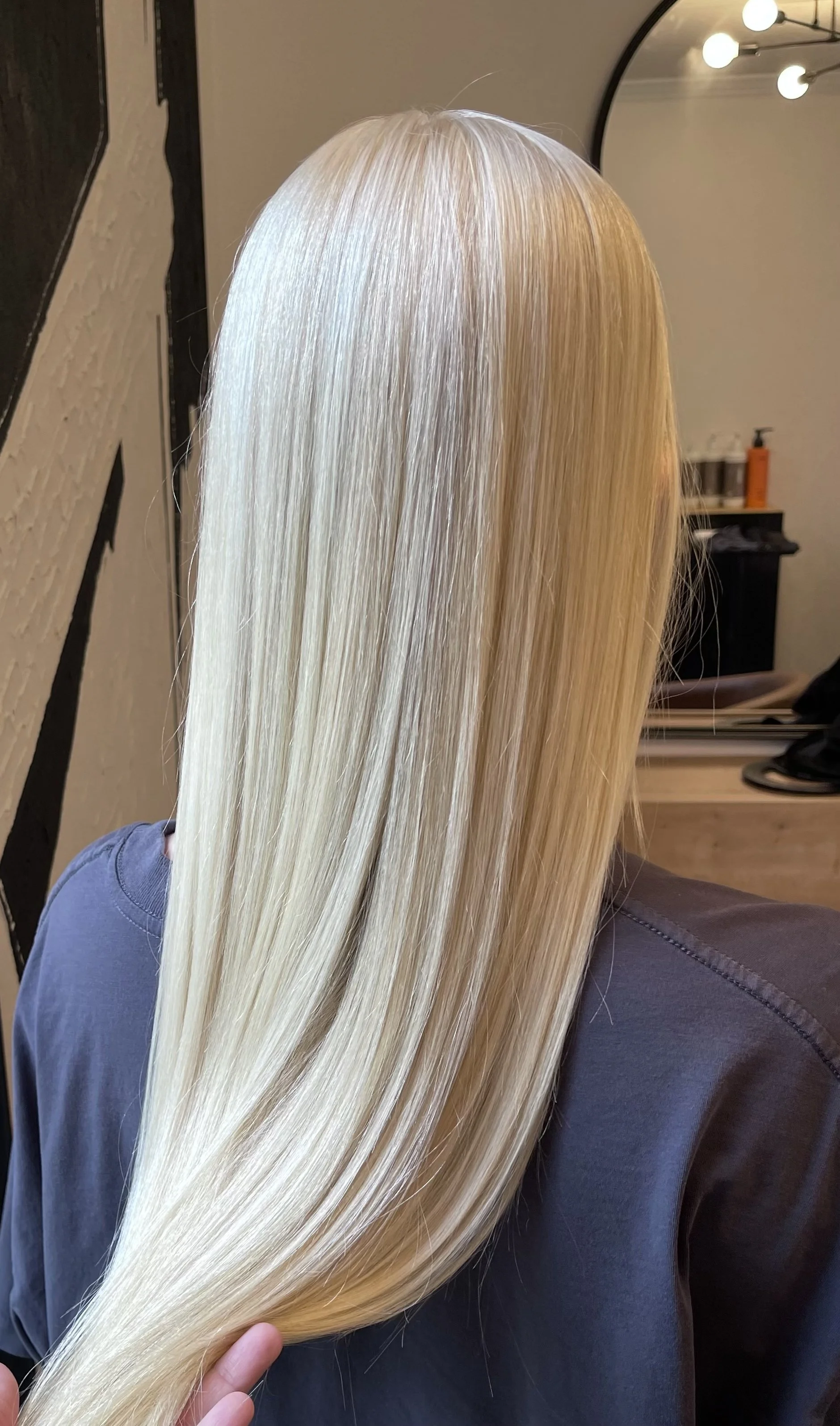 Person with long, straight, platinum blonde hair in a salon chair.