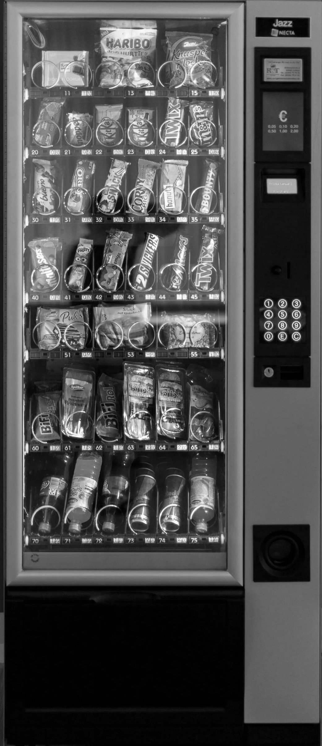 A vending machine filled with snacks such as candy bars, chips, and chocolates.