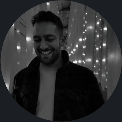 A man smiles in a string-lit hallway, captured in black and white—perfect for corporate video production Sydney style.