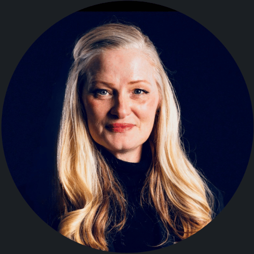 A woman with long blonde hair in a black top, smiling against a dark background—perfect for corporate video production Sydney.