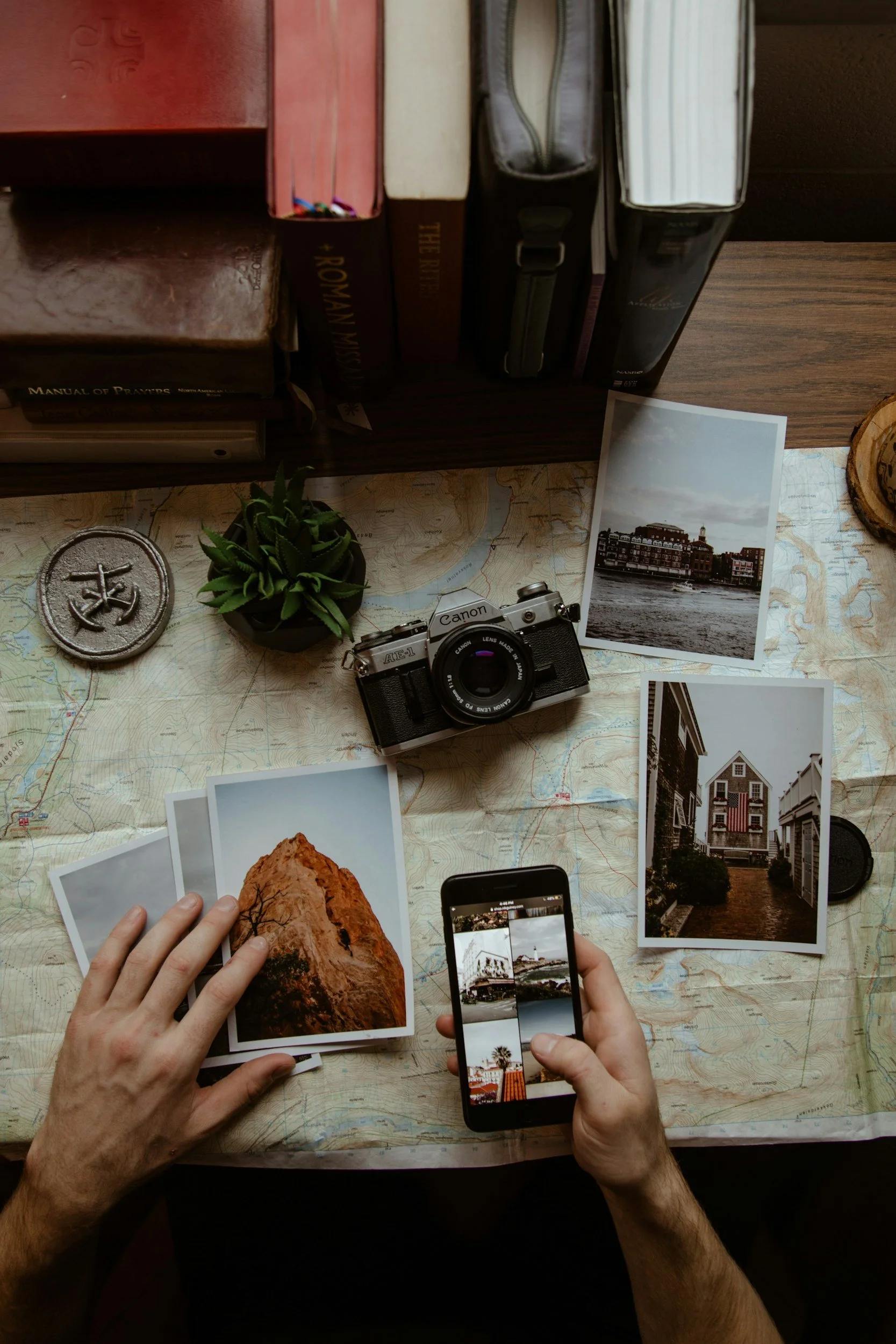 A person holds a smartphone taking a picture of printed photos preparing for digital scanning and photo organizing.