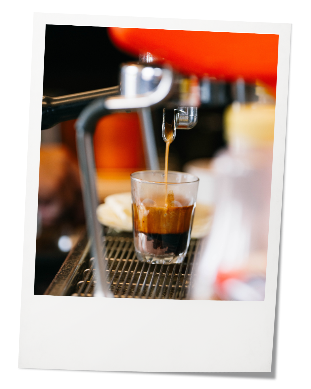Espresso shot being brewed from a coffee machine into a clear glass.