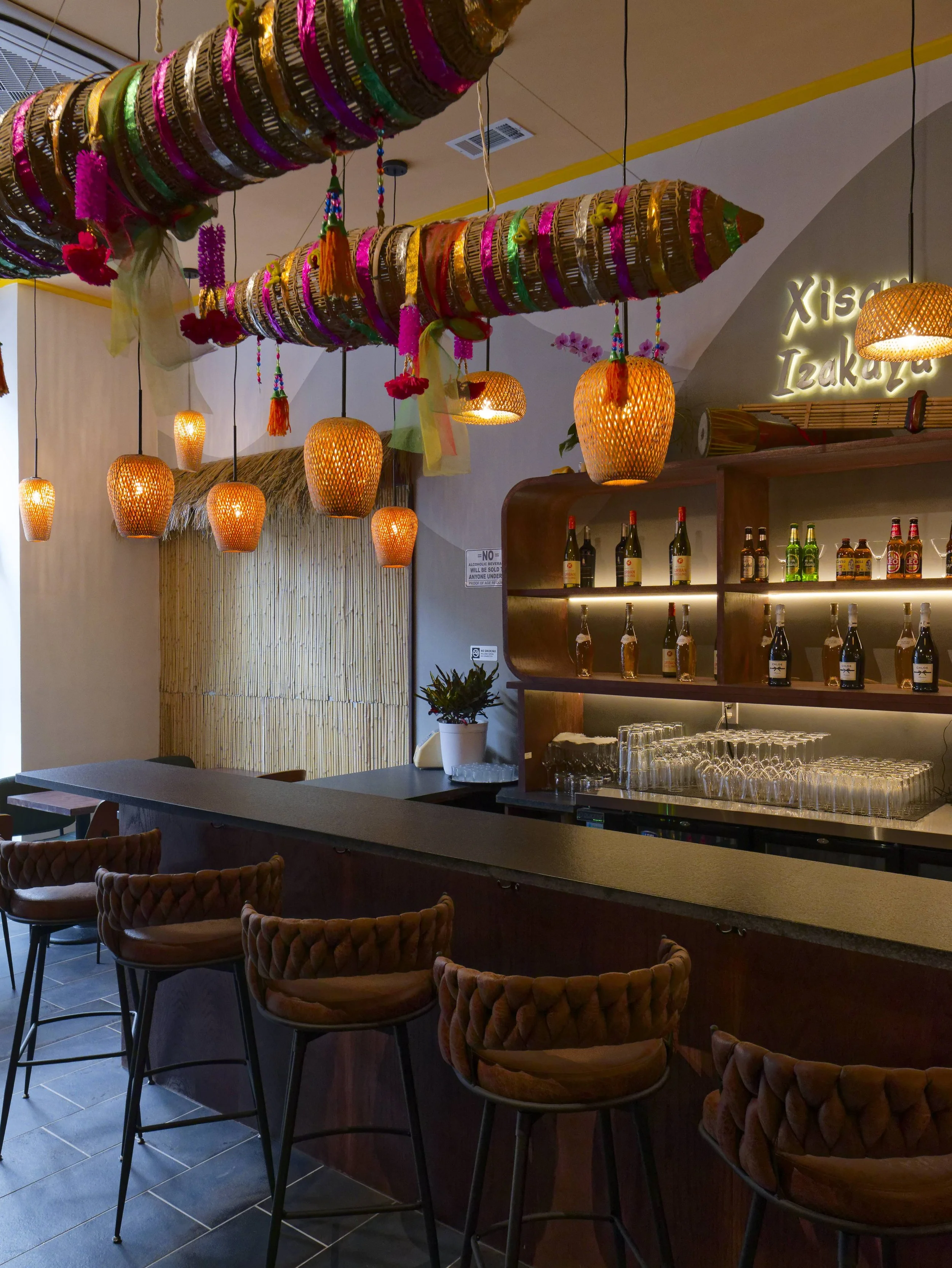 Creative commercial bar design featuring custom bamboo ceiling installations and woven pendant lights. Warm, inviting interior atmosphere for a Brooklyn restaurant. Renovation by XZ Design Build.