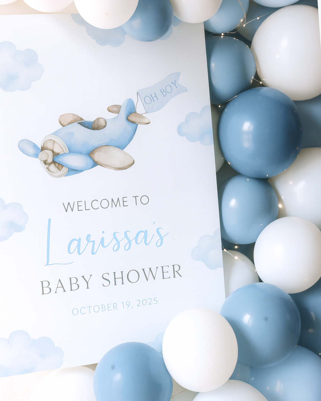 Baby shower invitation with airplane illustration, blue and white balloons, clouds background, welcoming a baby named Larissa on October 19, 2025.