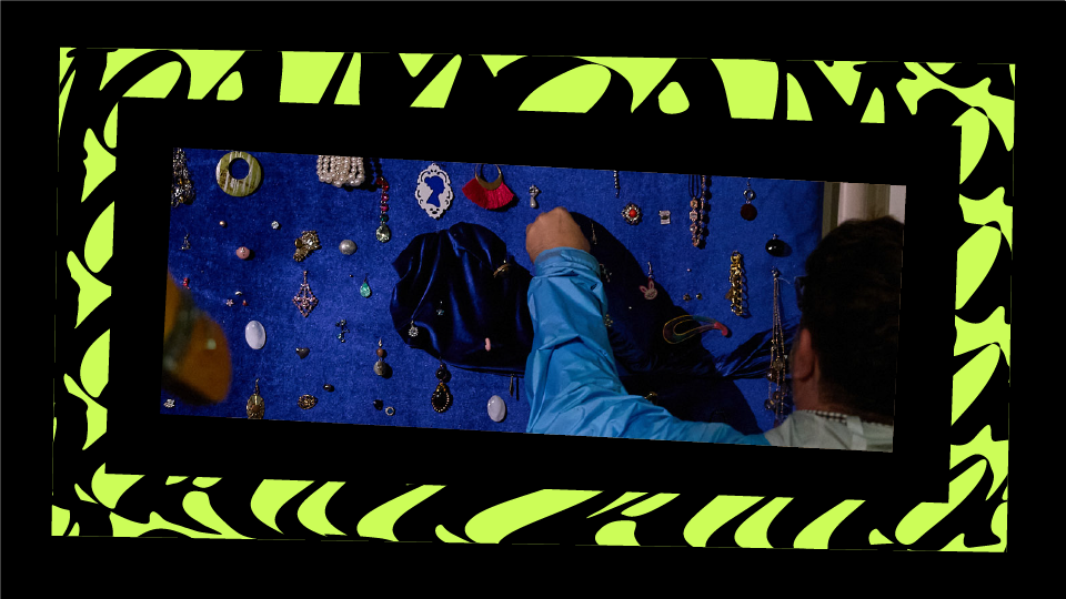 Person wearing a blue jacket browsing jewelry displayed on a blue velvet board.