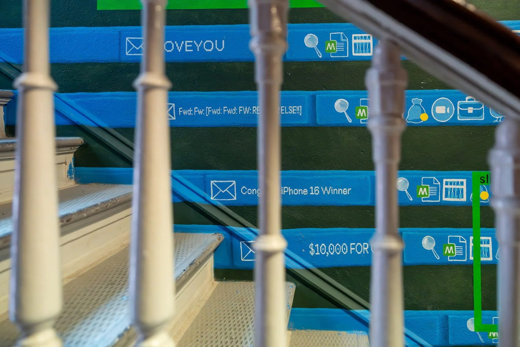 Colorful skateboard decks arranged on stairs viewed through a metal railing, with various designs and texts.
