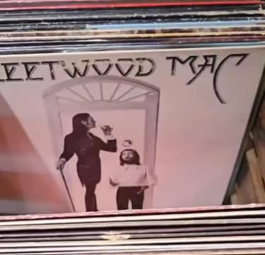 A record album cover showing a person in a suit with a cane and a hat, holding a glass, standing by a young child in a white dress inside a doorway. The text on the album is upside down, reading 'THE WU WU VDT'.
