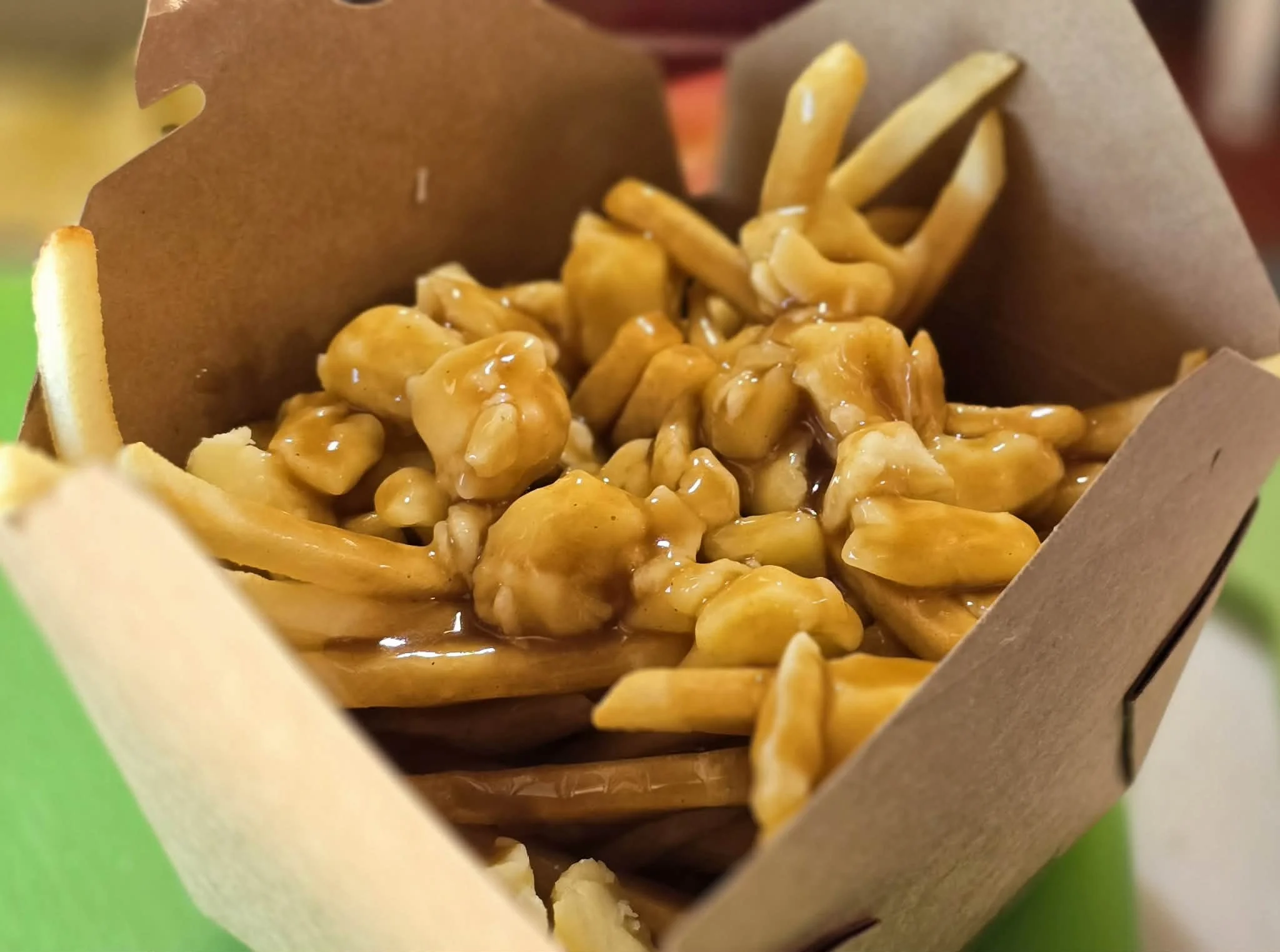 Fried chicken with gravy, French fries, and a small bowl of macaroni and cheese in a food tray.