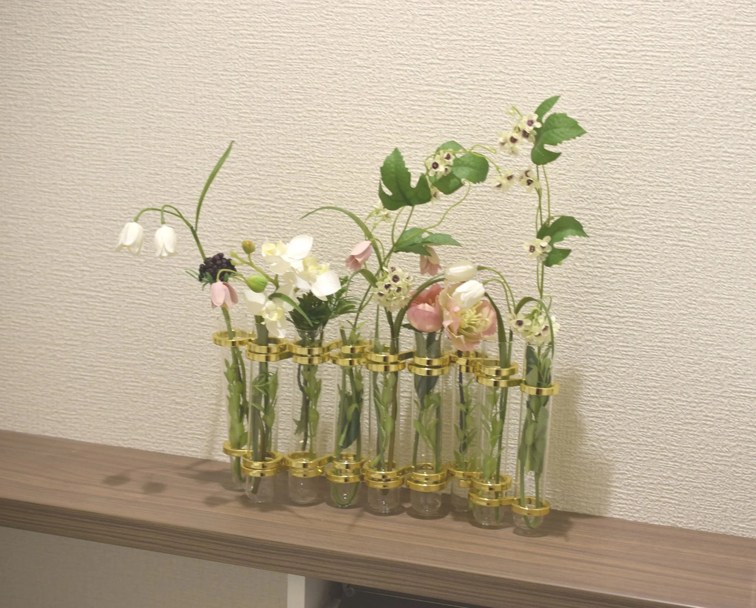 ガラスの花瓶にさまざまな花と植物が飾られている。