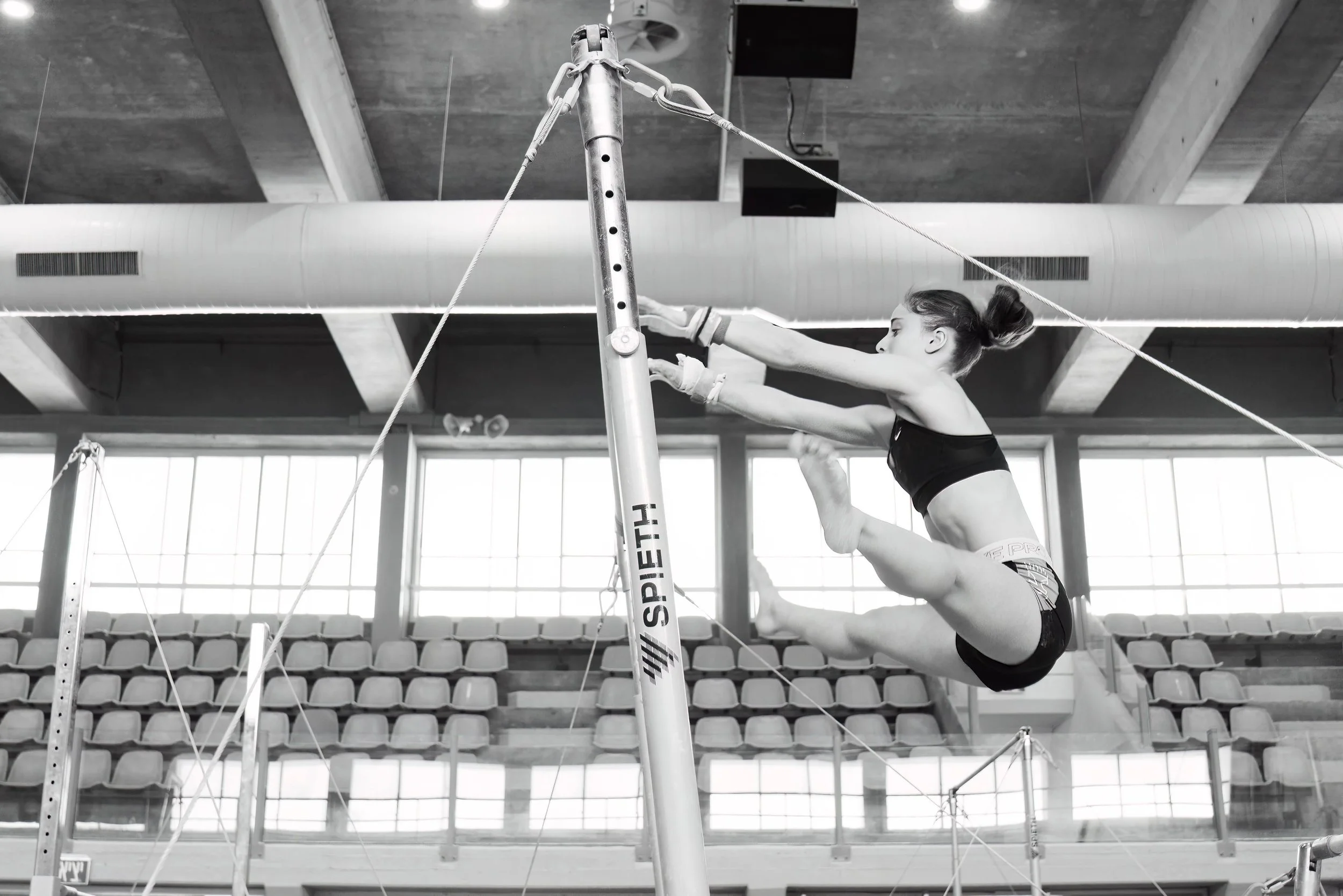 High-speed action shot on the Uneven Bars, showcasing strength and precision.
