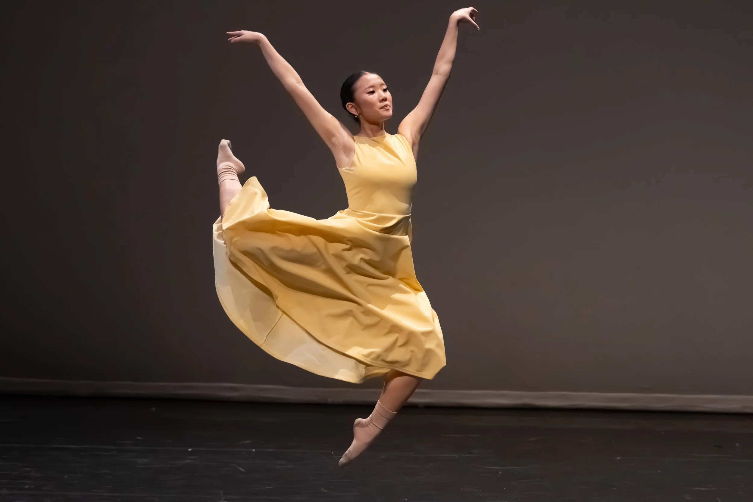 Professional dance photography of a ballerina in a yellow costume performing on stage | Tri City Dance Center