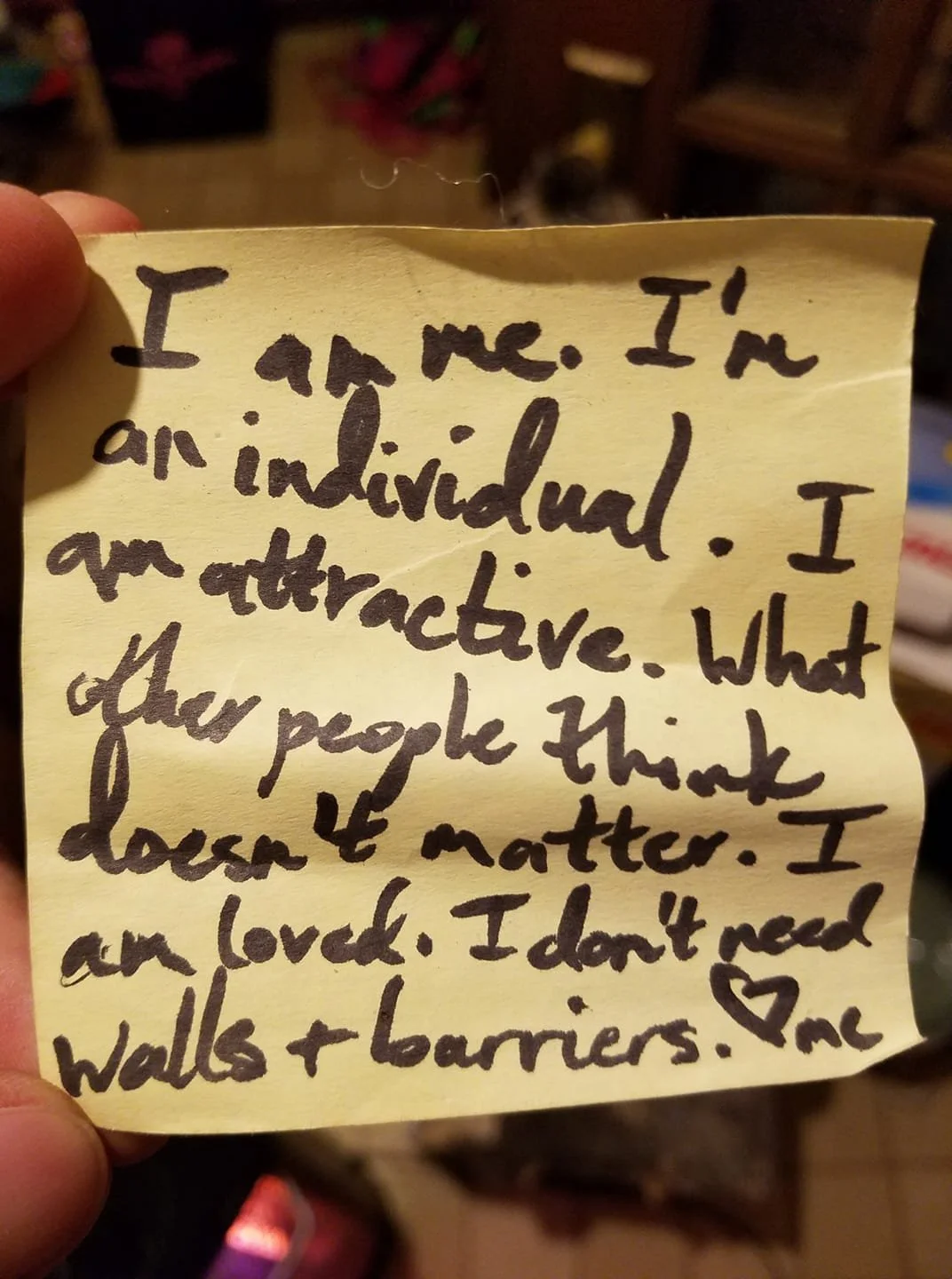 Yellow, crinkled post-it that says, "I am me. I'm an individual. I am attractive. What other people think doesn't matter. I am loved. I don't need walls & barriers. <3 me"