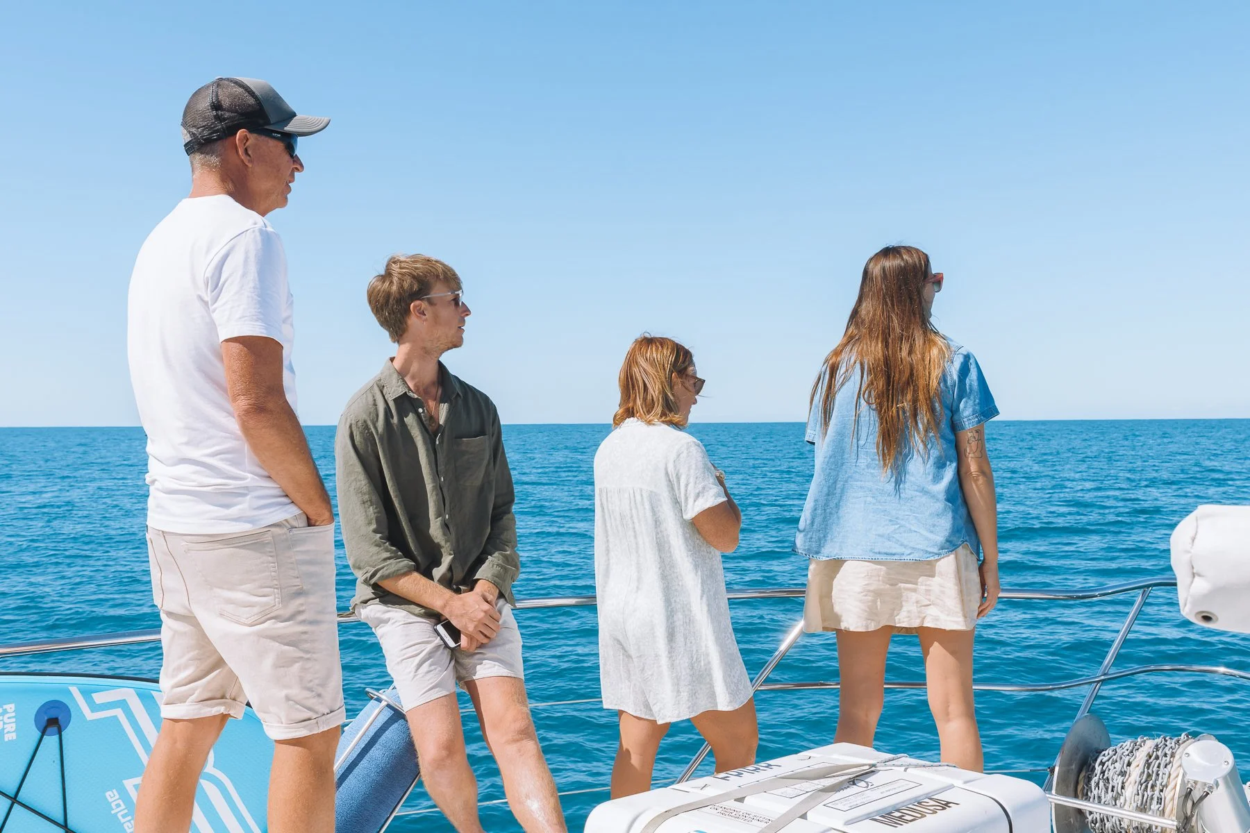 Four people on a boat looking out at the ocean during daytime.