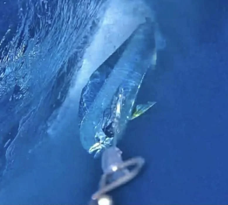 Close-up of an ice climber's hand and ice axe gripping a sharp, icy surface attached to a vertical ice wall.