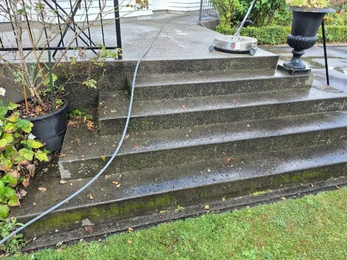 Wet outdoor concrete steps with a garden hose on a rainy day.